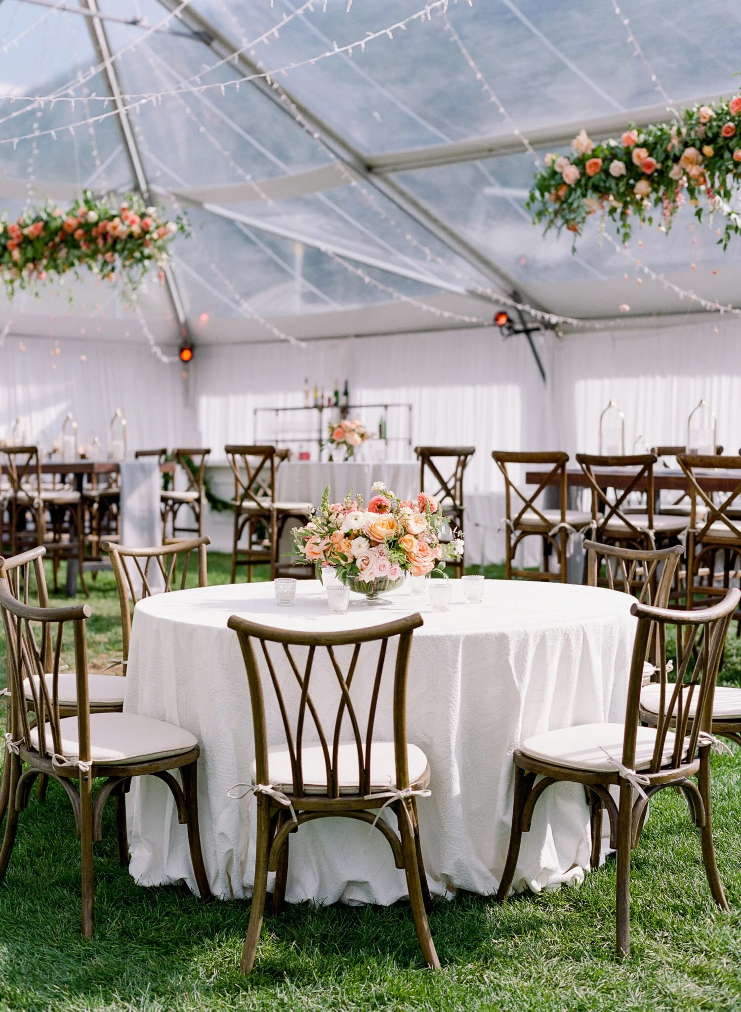 Romantic tented reception with floral centerpieces and hanging greenery.