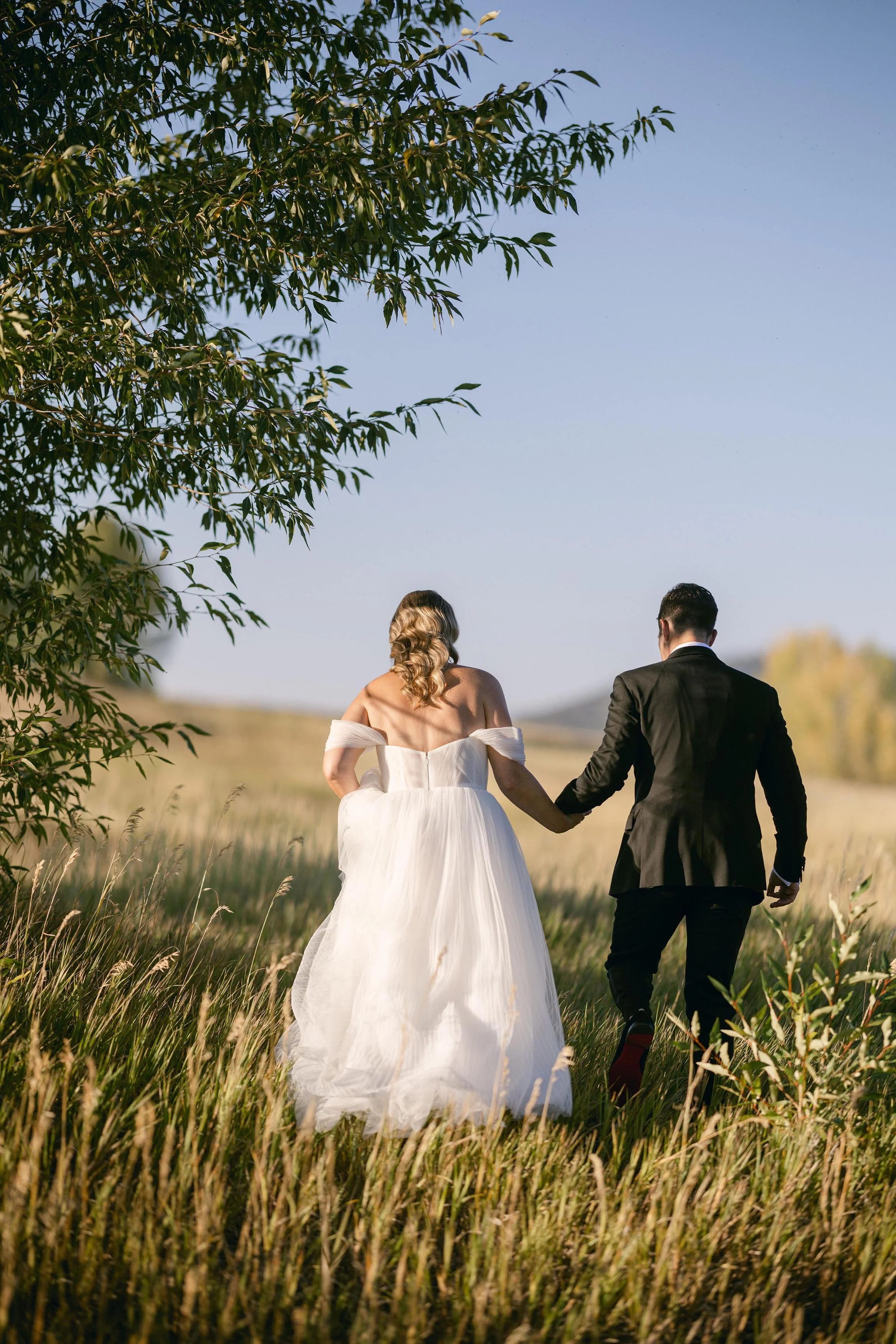 a bride and groom holding hands walking the fields of steamboat springs colorado