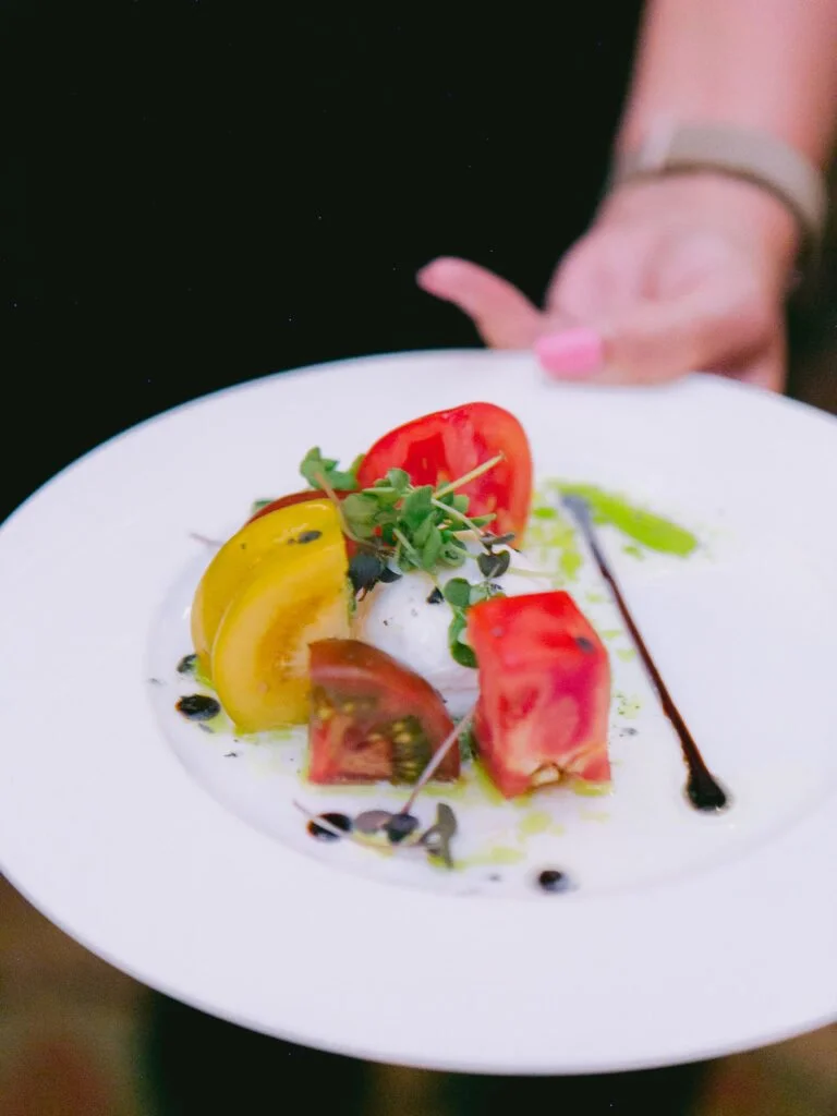 Colorful heirloom tomato salad served with microgreens, highlighting eco-friendly wedding tips for sustainable catering.