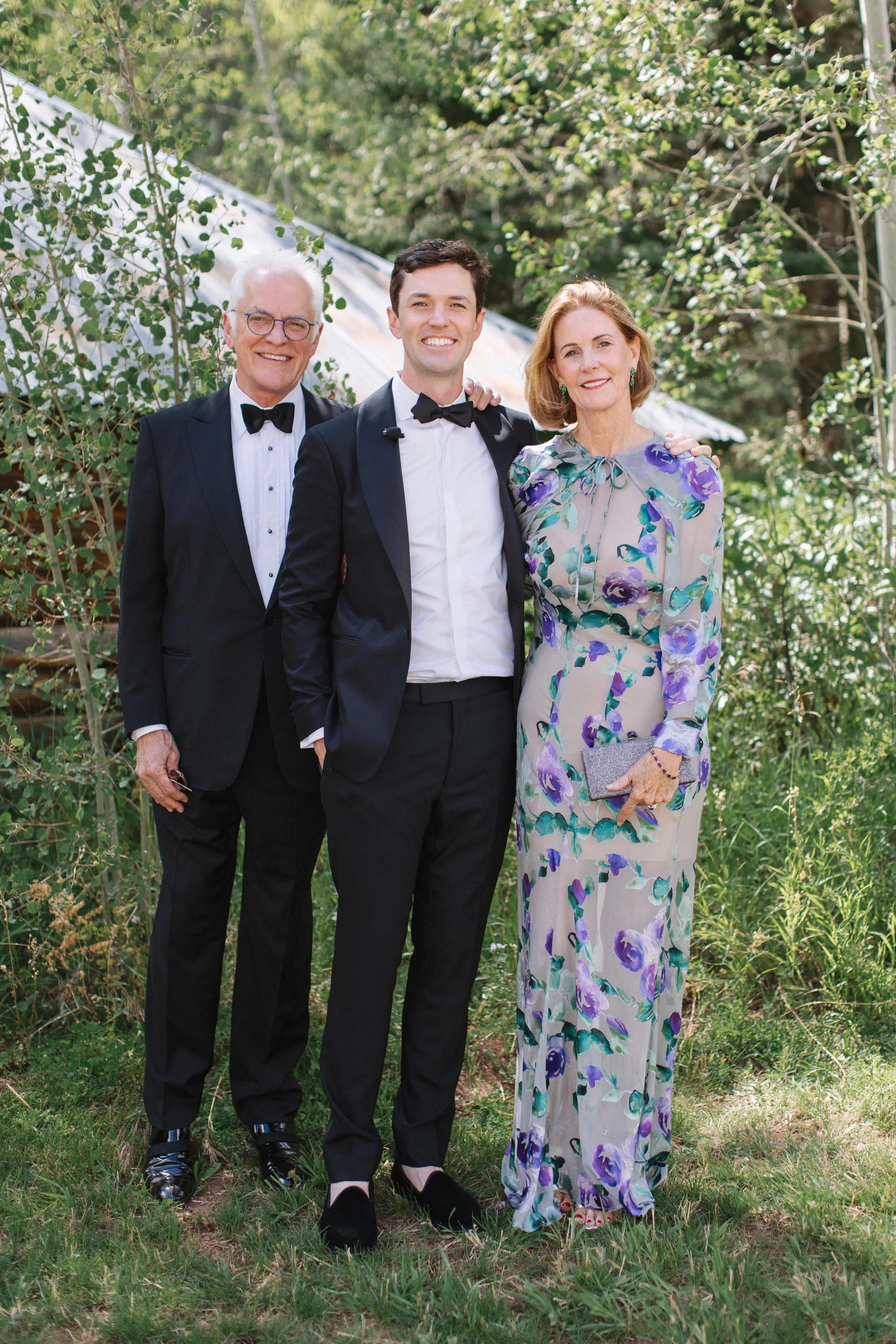 a groom posing with his mom and dad on the day of his wedding