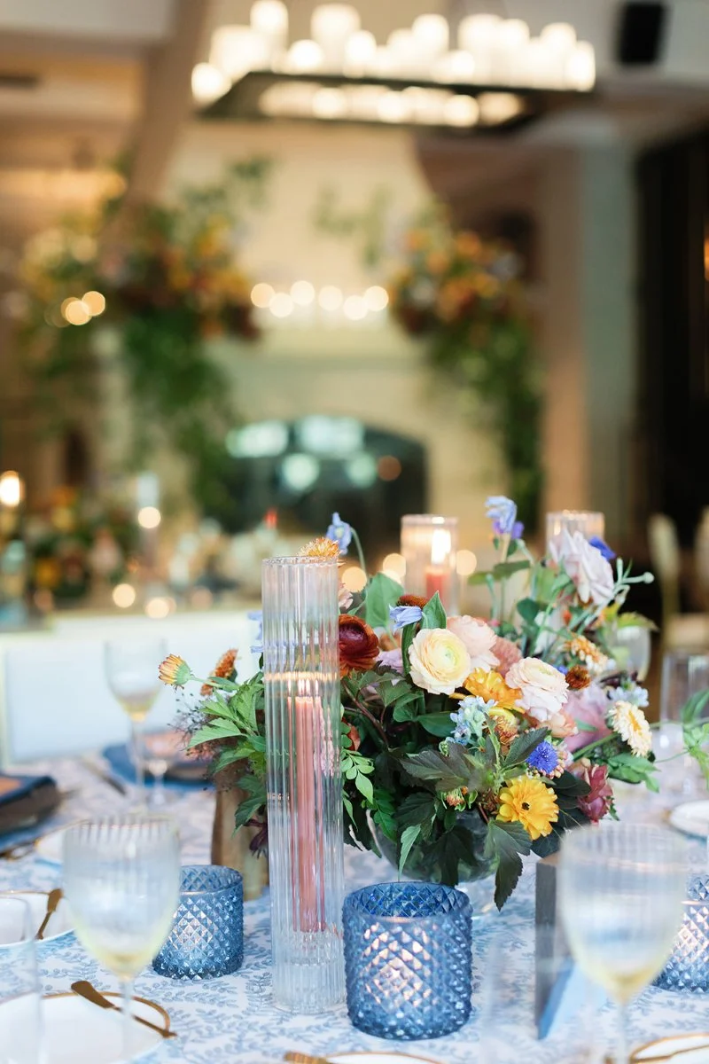 Elegant reception tablescape with colorful florals, glowing candlelight, and layered details creating a romantic atmosphere.