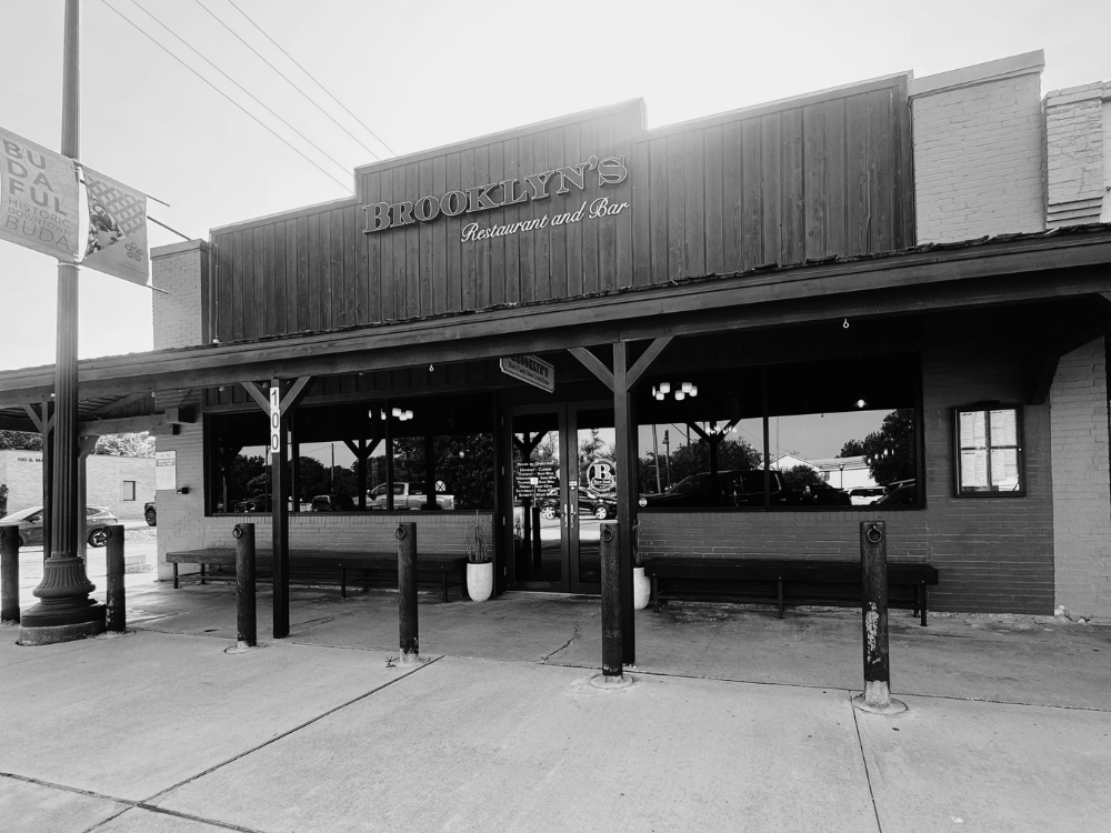 Exterior of Brooklyn's Restaurant and Bar, with benches and bollards outside, and a sign next to the entrance.