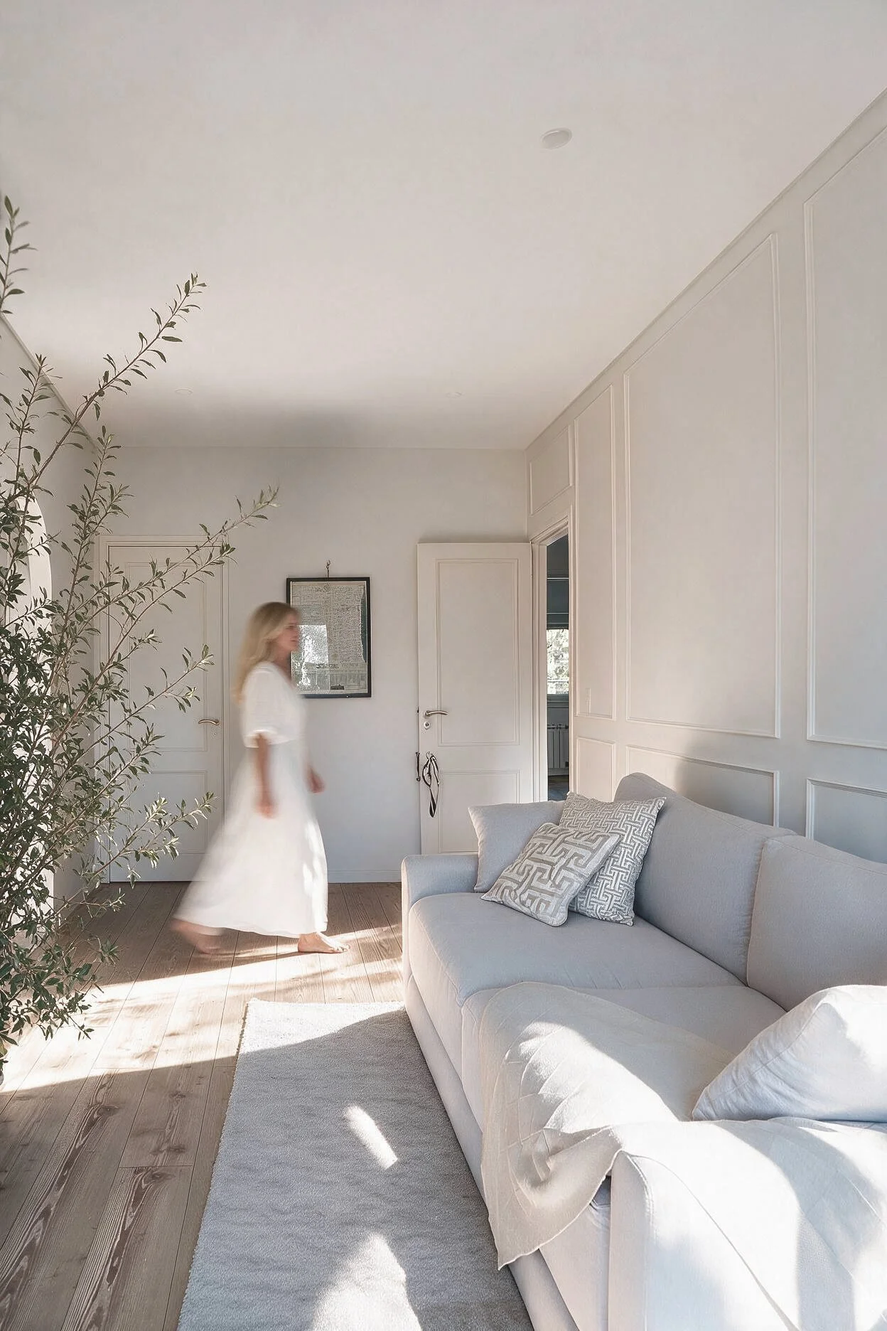 Living luminoso con sillón blanco, almohadones estampados, cuadro enmarcado y planta junto a ventanal — proyecto de interiorismo en Buenos Aires