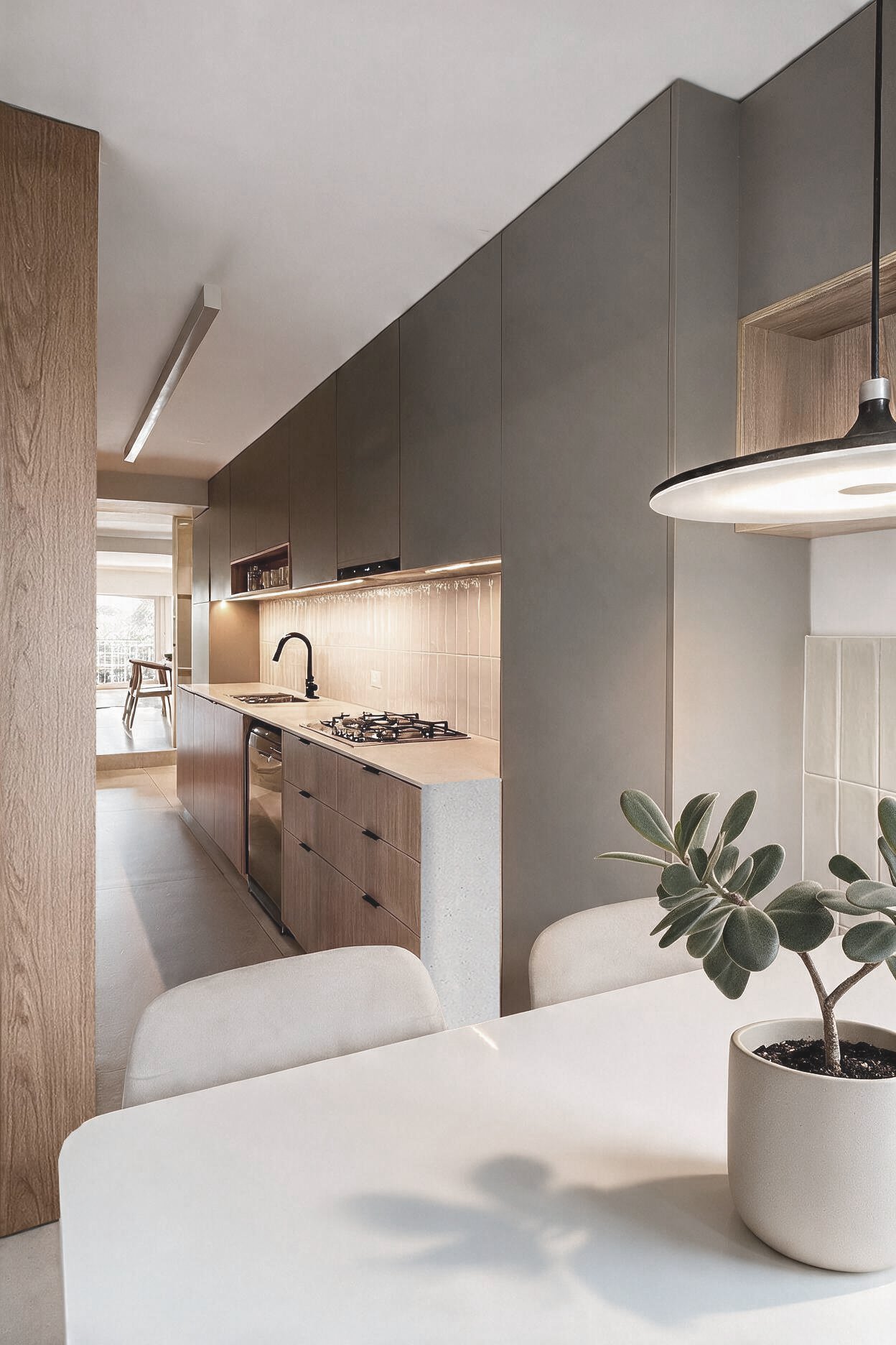 Cocina con muebles grises, revestimiento beige, cocina empotrada y grifería negra, con comedor y planta — proyecto de reforma en Buenos Aires