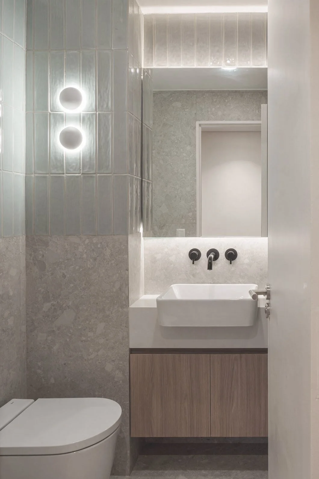 Baño con inodoro blanco, bacha rectangular, espejo grande y grifería de pared sobre revestimiento claro — proyecto de reforma en Buenos Aires