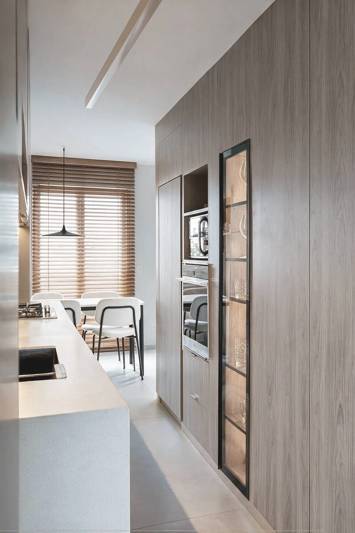 Cocina con pared revestida en madera, horno empotrado, comedor con sillas blancas, mesada blanca con bacha y ventana con persianas de madera — proyecto de reforma en CABA