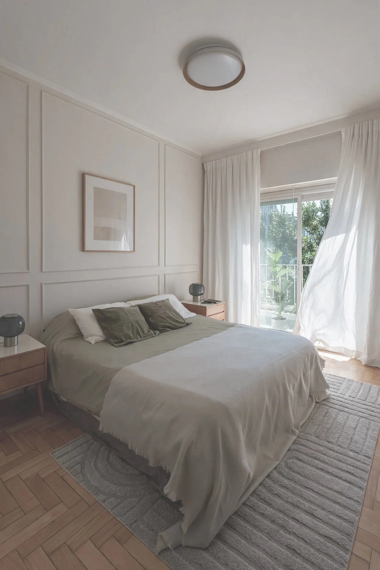 Dormitorio con cama blanca, almohadones verdes, mesas de luz con lámparas grises y puerta corrediza con vista al jardín — proyecto de interiorismo en CABA