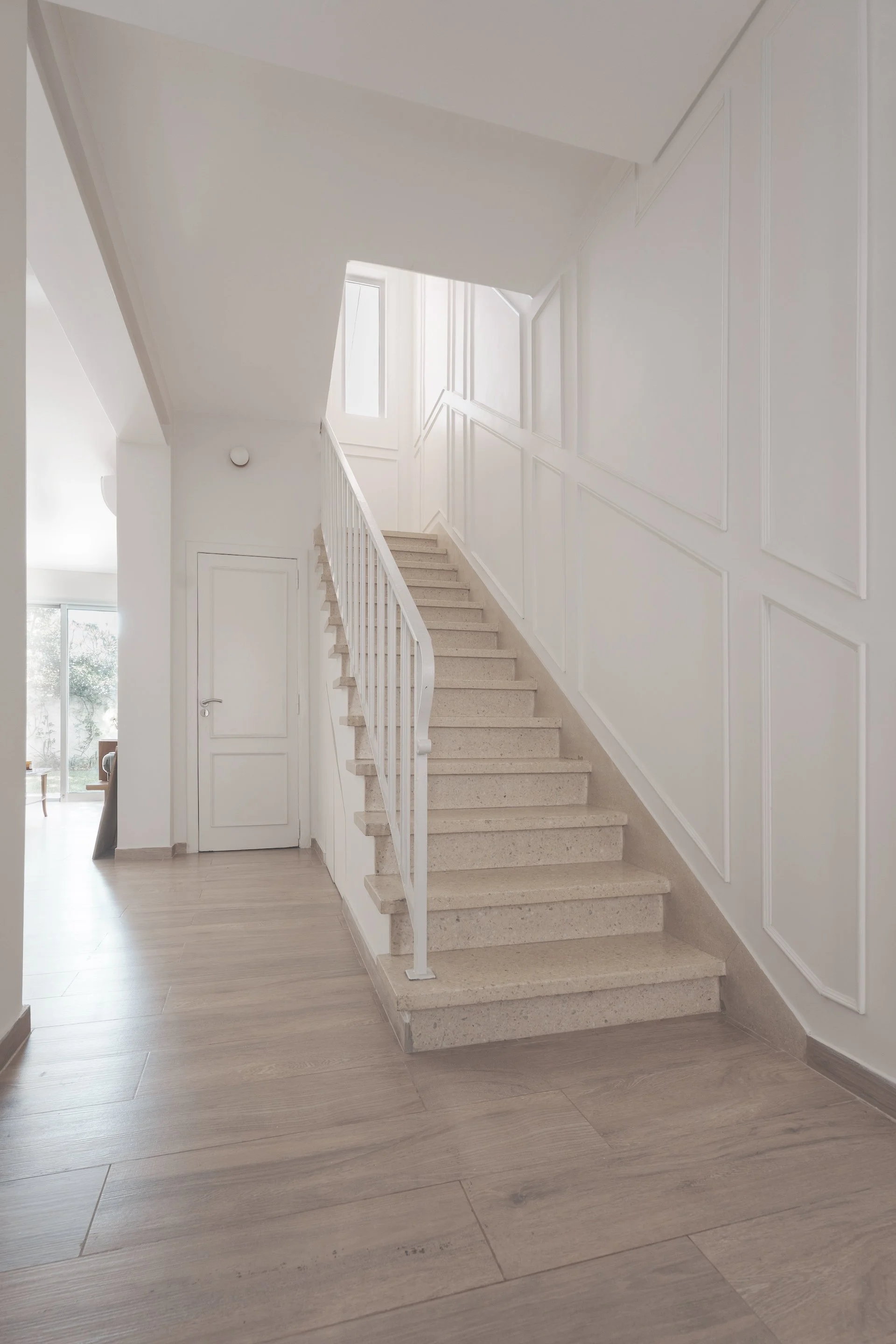 Escalera en vivienda moderna y luminosa, con paredes blancas y piso de madera clara — proyecto de reforma en CABA
