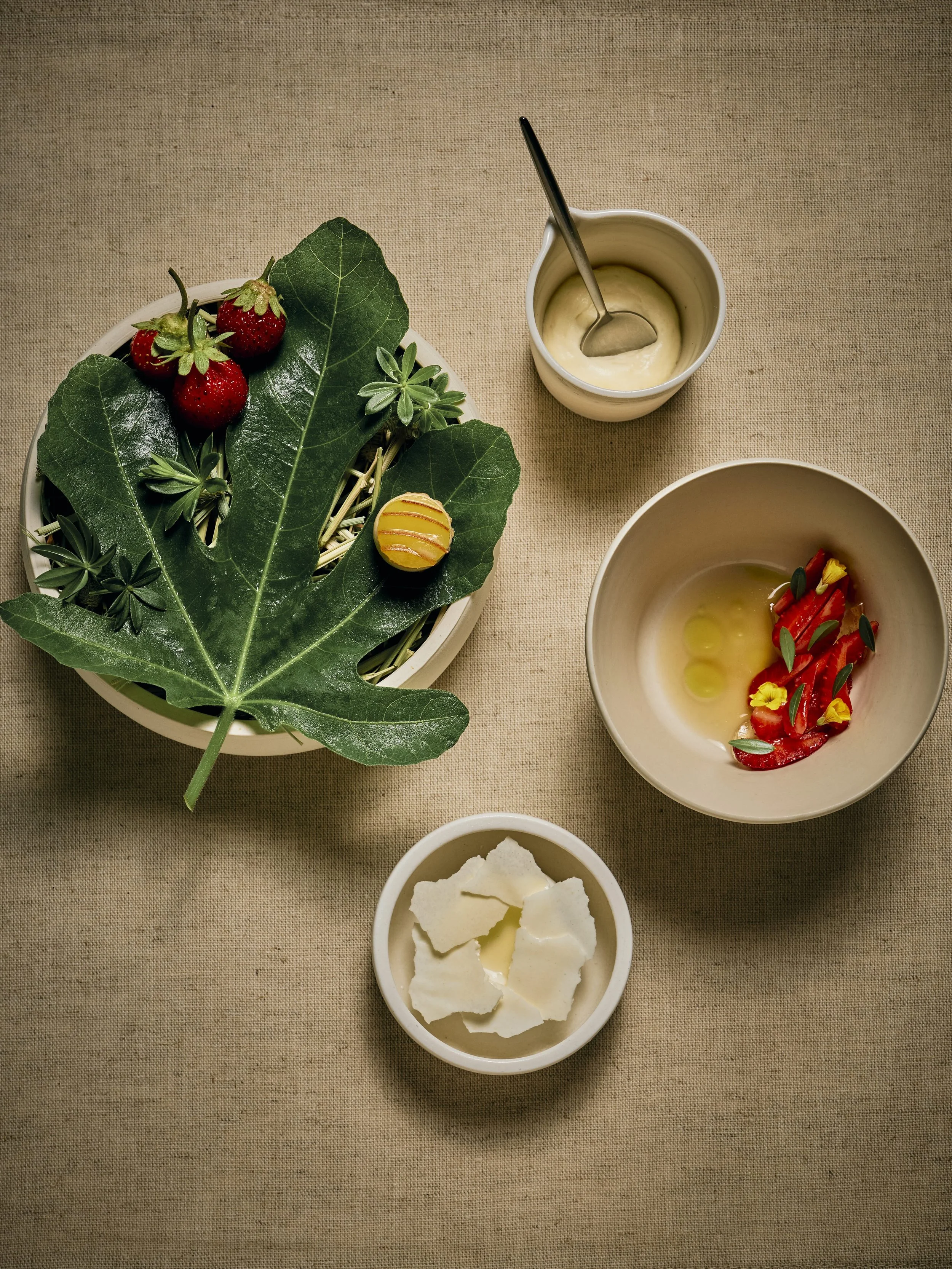 Strawberries from meadowood with clotted cream, spicebush and fig leaves.