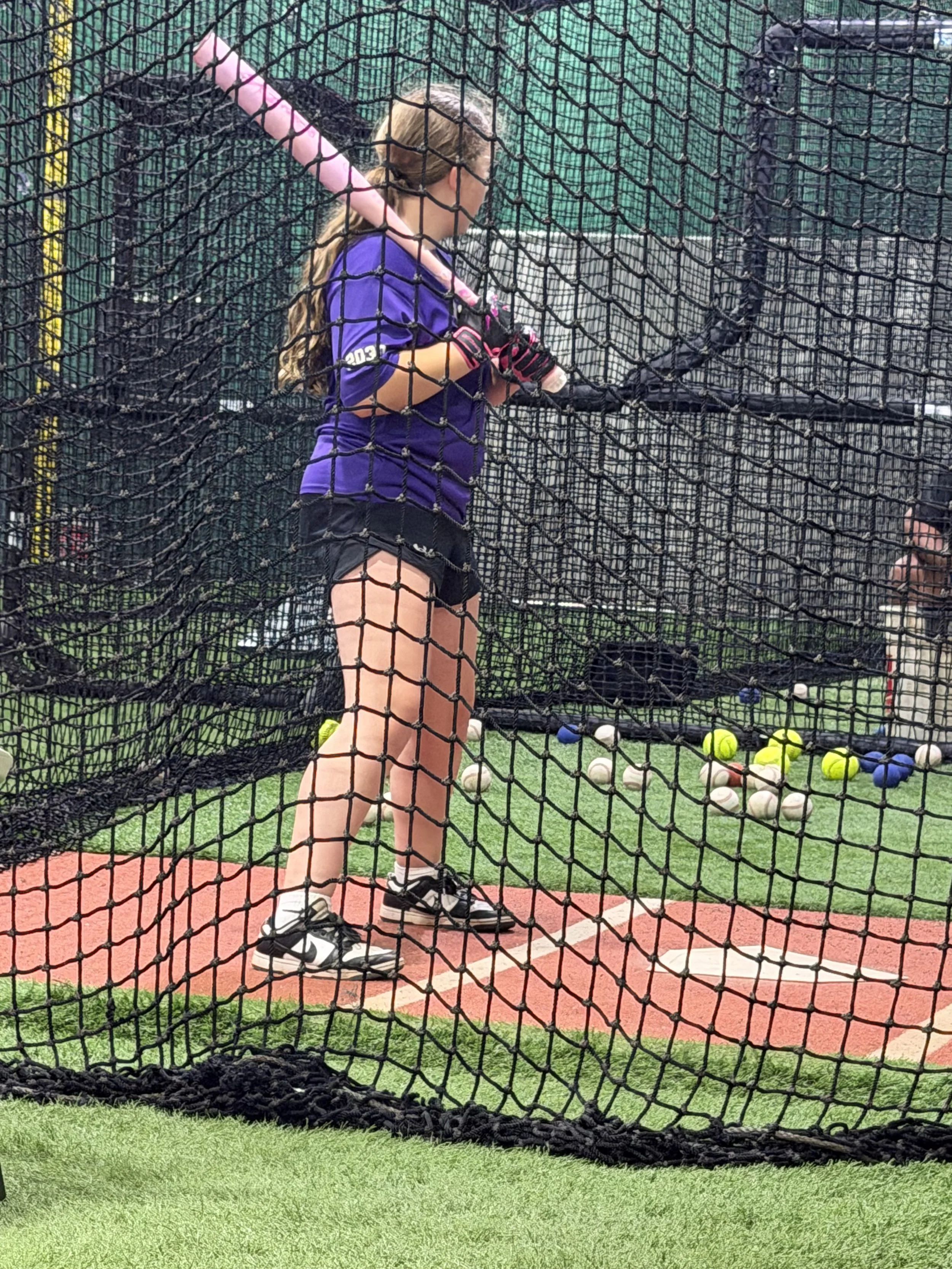 Youth softball player training with coach Manny Oliveira during a private hitting lesson at Line Drive Indoor Batting in Jupiter, Florida.