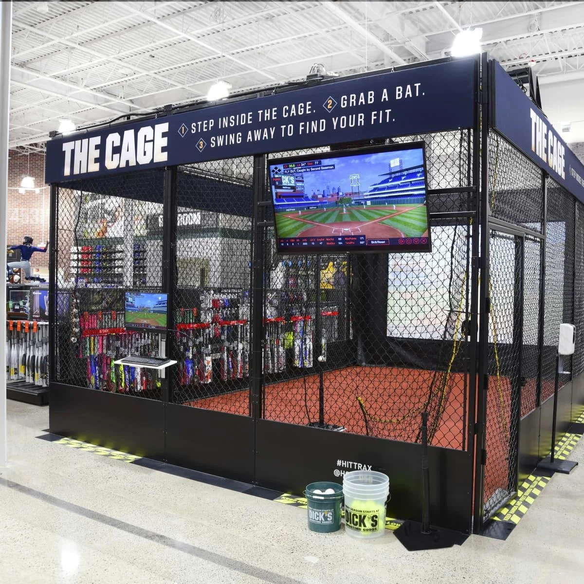 Baseball player using a HitTrax batting cage inside a DICK’S sports training area.