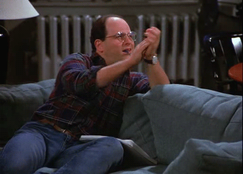 A man sitting on a couch, clapping his hands and appearing very happy or excited.