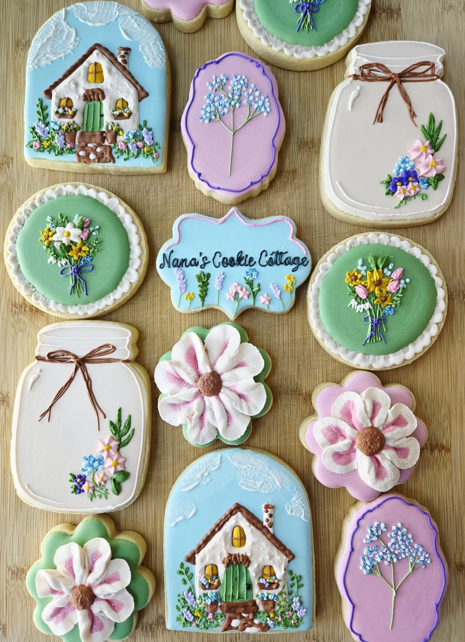 Decorated cookies with floral and house designs, some shaped like flowers and jars, on a wooden surface.