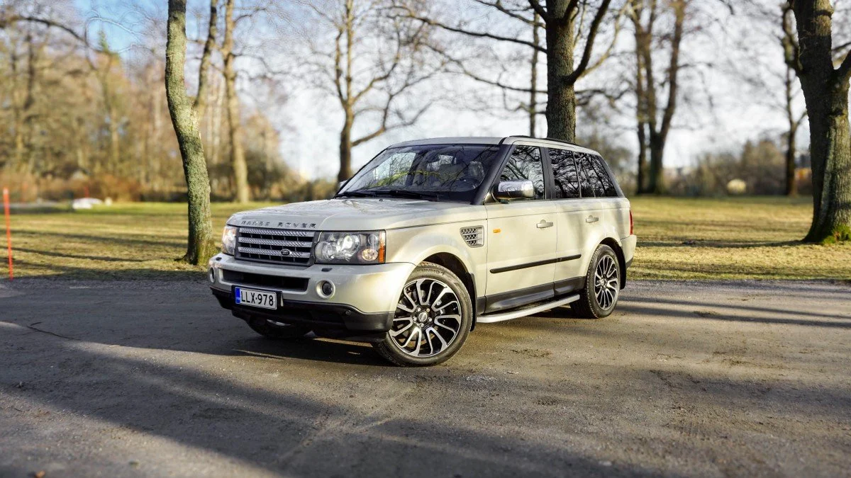 Silver Range Rover parked on a tree-lined park road