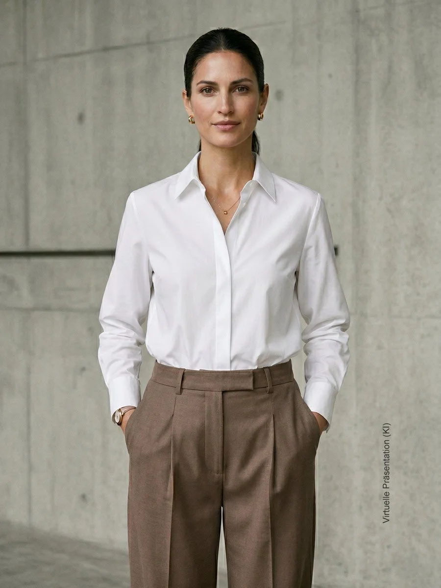Elegante Frau in einer maßgeschneiderten weißen Bluse und brauner Stoffhose als Repräsentantin für die Identity Essentials im Atelier Burcu in Essen-Werden.