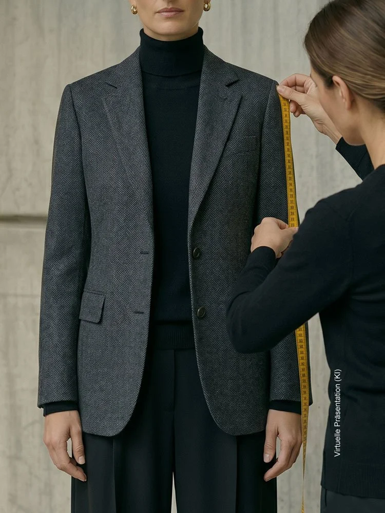 Schneiderin beim Maßnehmen der Schulterpartie mit einem gelben Maßband an einem maßgeschneiderten dunkelgrauen Fischgrät-Blazer im Atelier Burcu in Essen-Werden.
