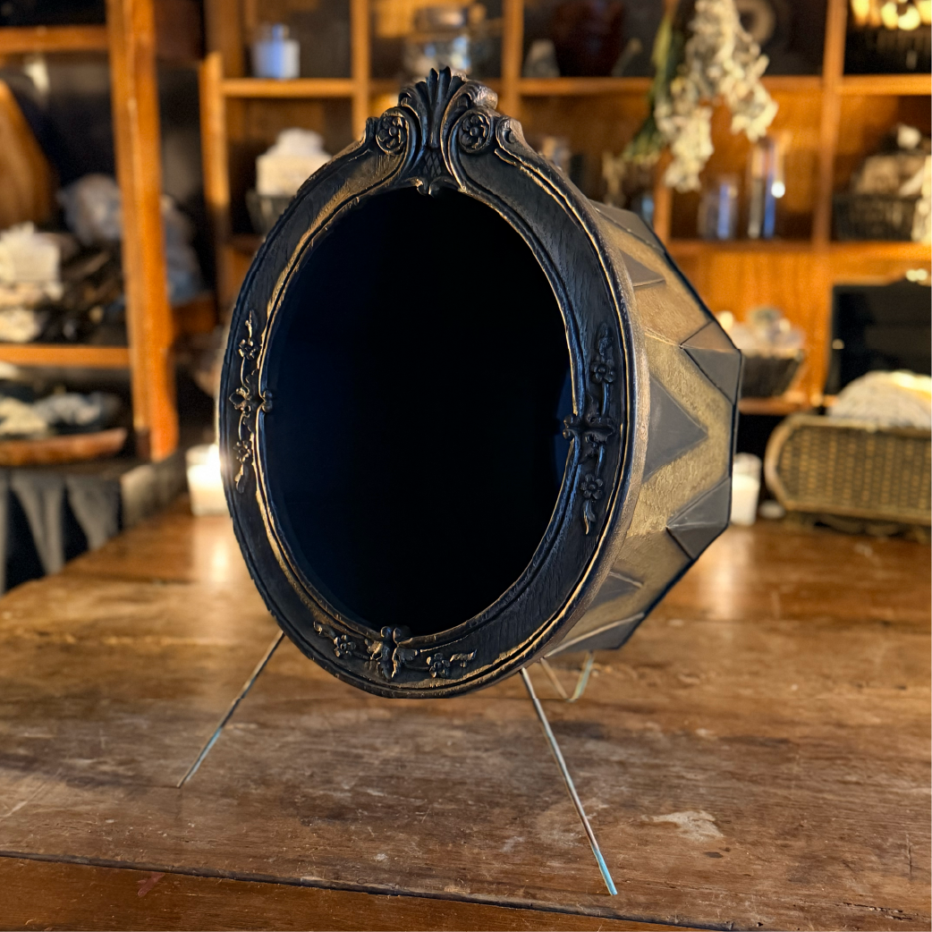 Black scrying mirror in an ornate faceted stand, labeled ‘Scrywells’”