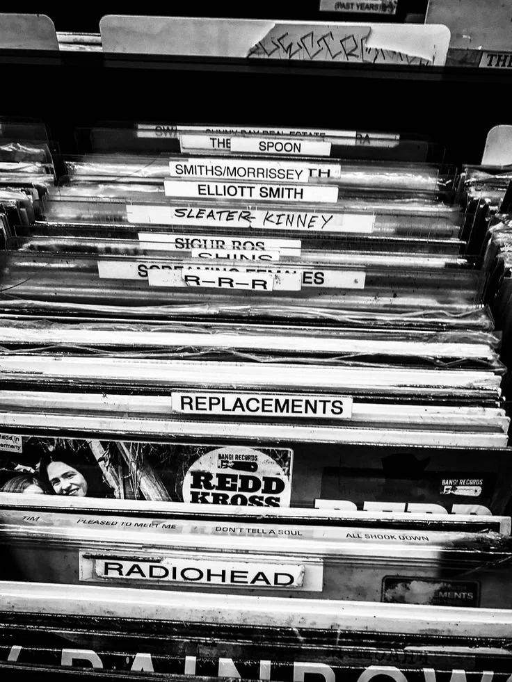 Pila de discos de vinilo en blanco y negro con separadores de artistas ordenados alfabéticamente en una bandeja de disquería — registro de marca y derechos de autor para músicos, Fuzz Legal.