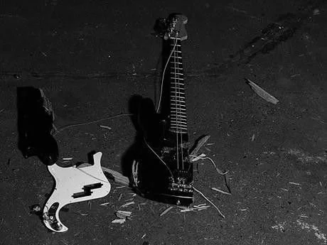 Bajo eléctrico destrozado en el suelo, en blanco y negro, con el cuerpo separado del mástil — representación judicial y resolución de conflictos legales para artistas, Fuzz Legal.