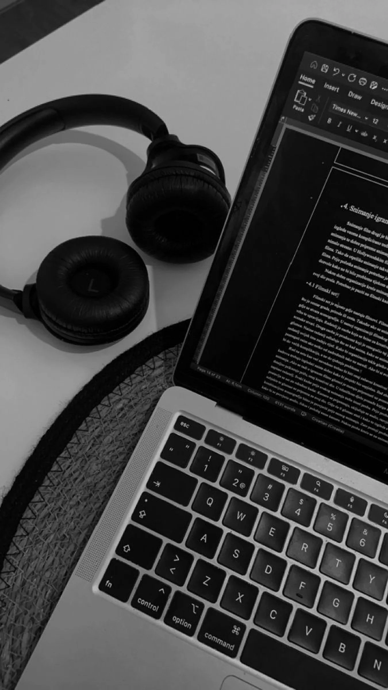 Auriculares de estudio apoyados junto a una notebook abierta con texto en pantalla, en blanco y negro — asesoramiento legal continuo para artistas independientes, Fuzz Legal.
