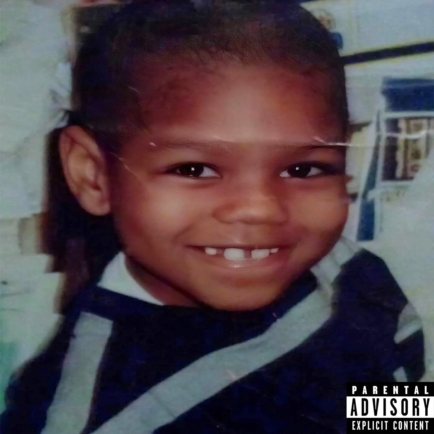 Close-up of a smiling young boy with missing front teeth, wearing a black and white striped hoodie.