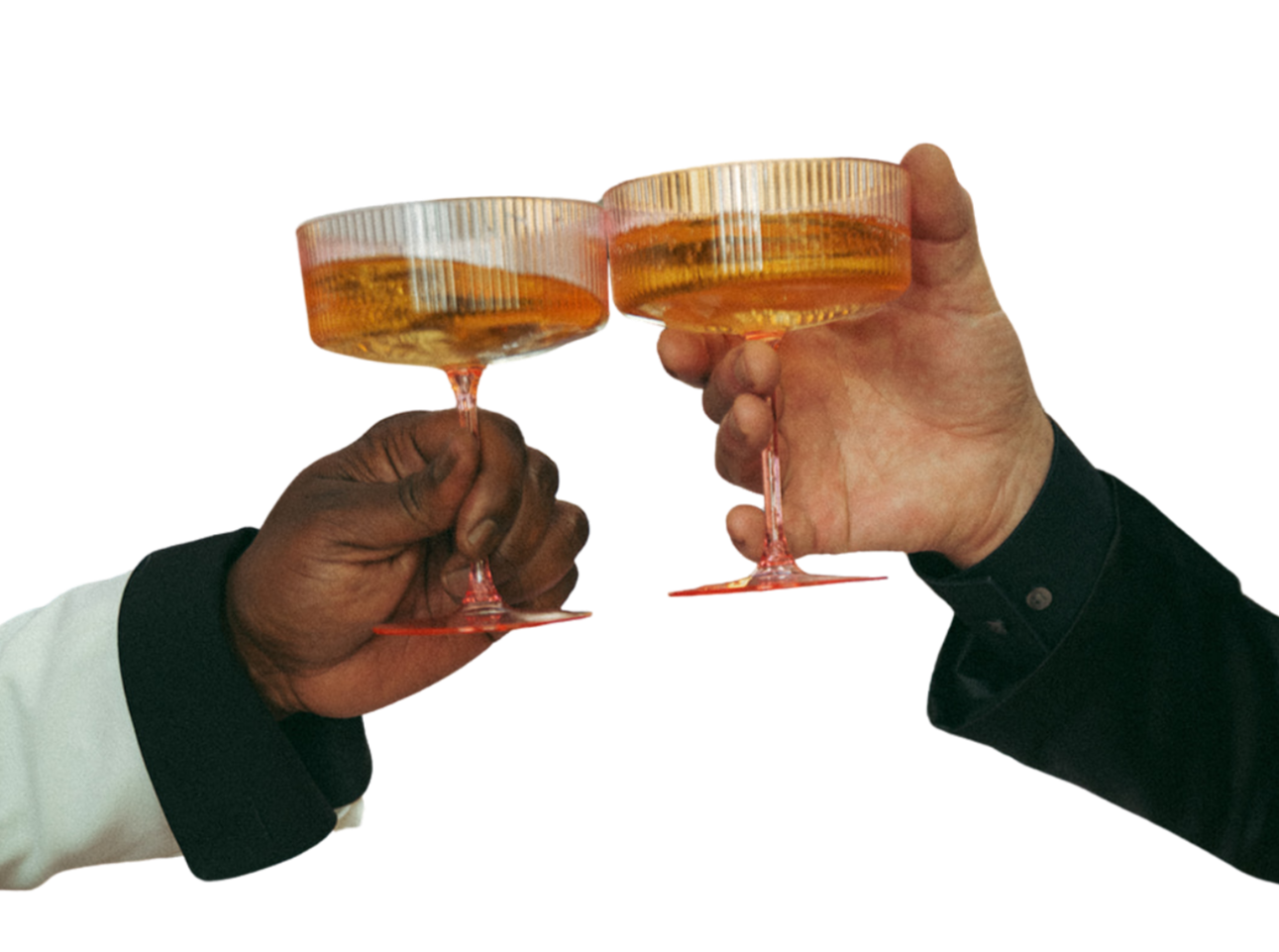 Two people toasting with champagne glasses filled with an amber-colored drink.