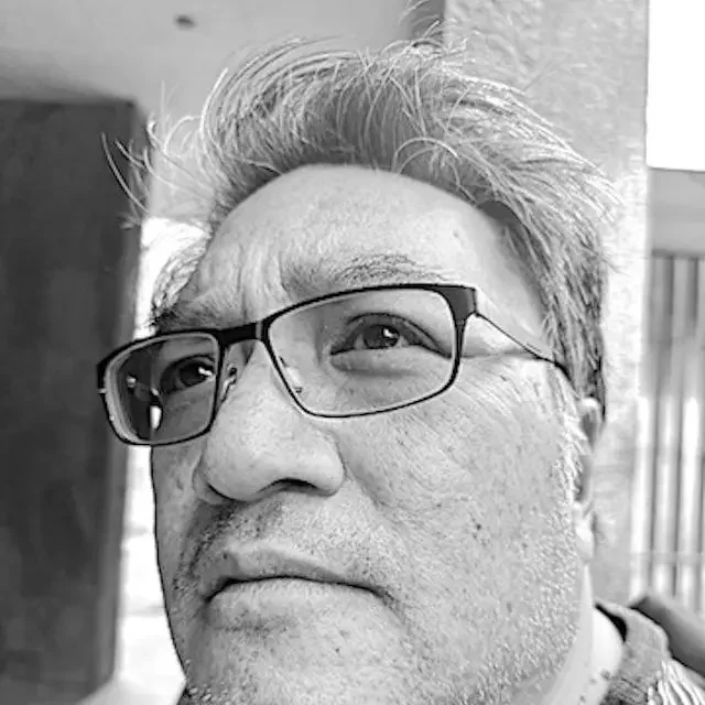 Close-up of a middle-aged man with glasses, gray hair, and a thoughtful expression.