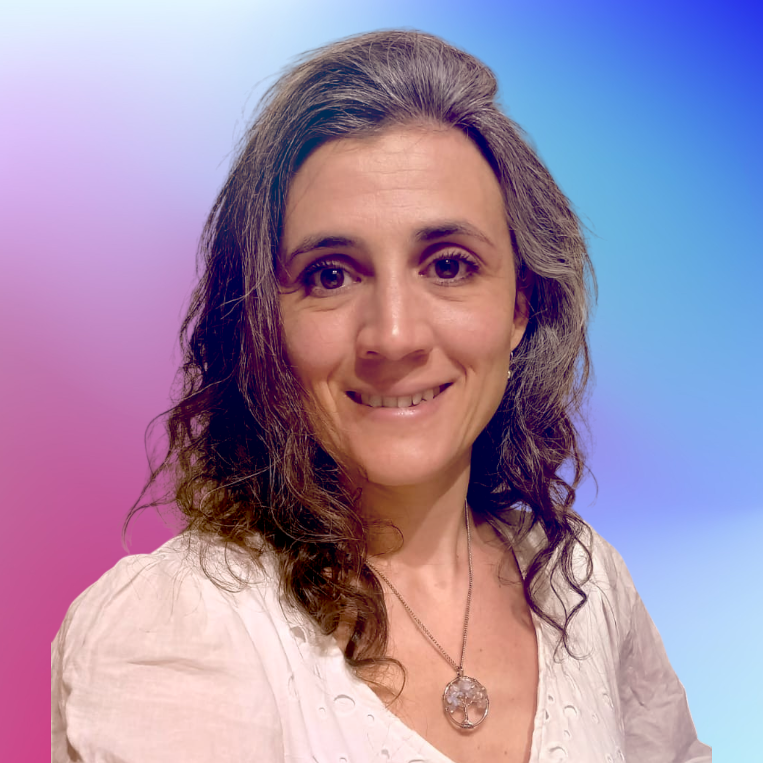 Mujer con cabello ondulado y gris, sonriente, usando un collar con colgante de árbol y blusa blanca, fondo de colores degradados azul, púrpura y rosa.