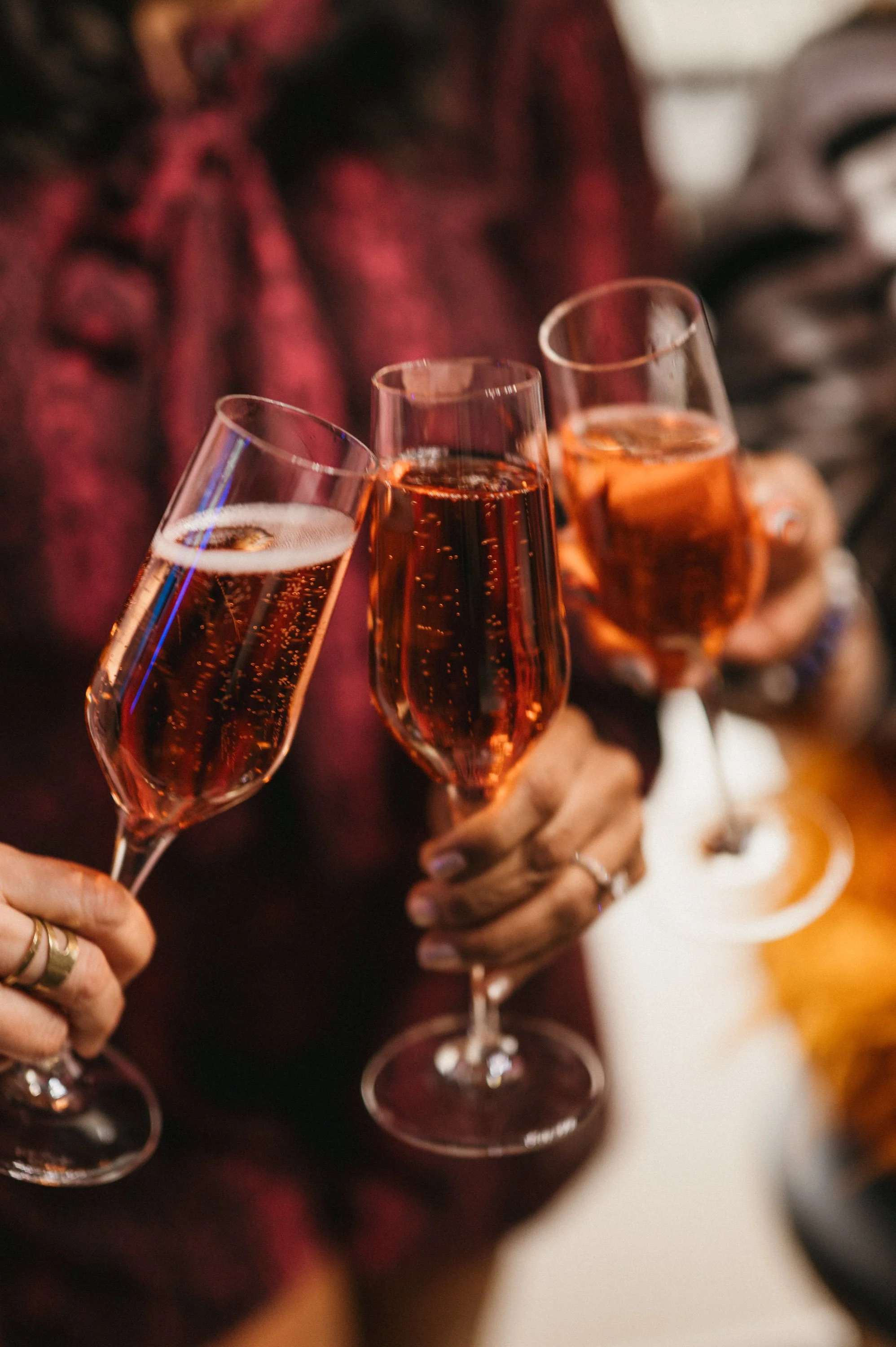 Several people holding glasses of pink sparkling wine at a celebration or gathering.
