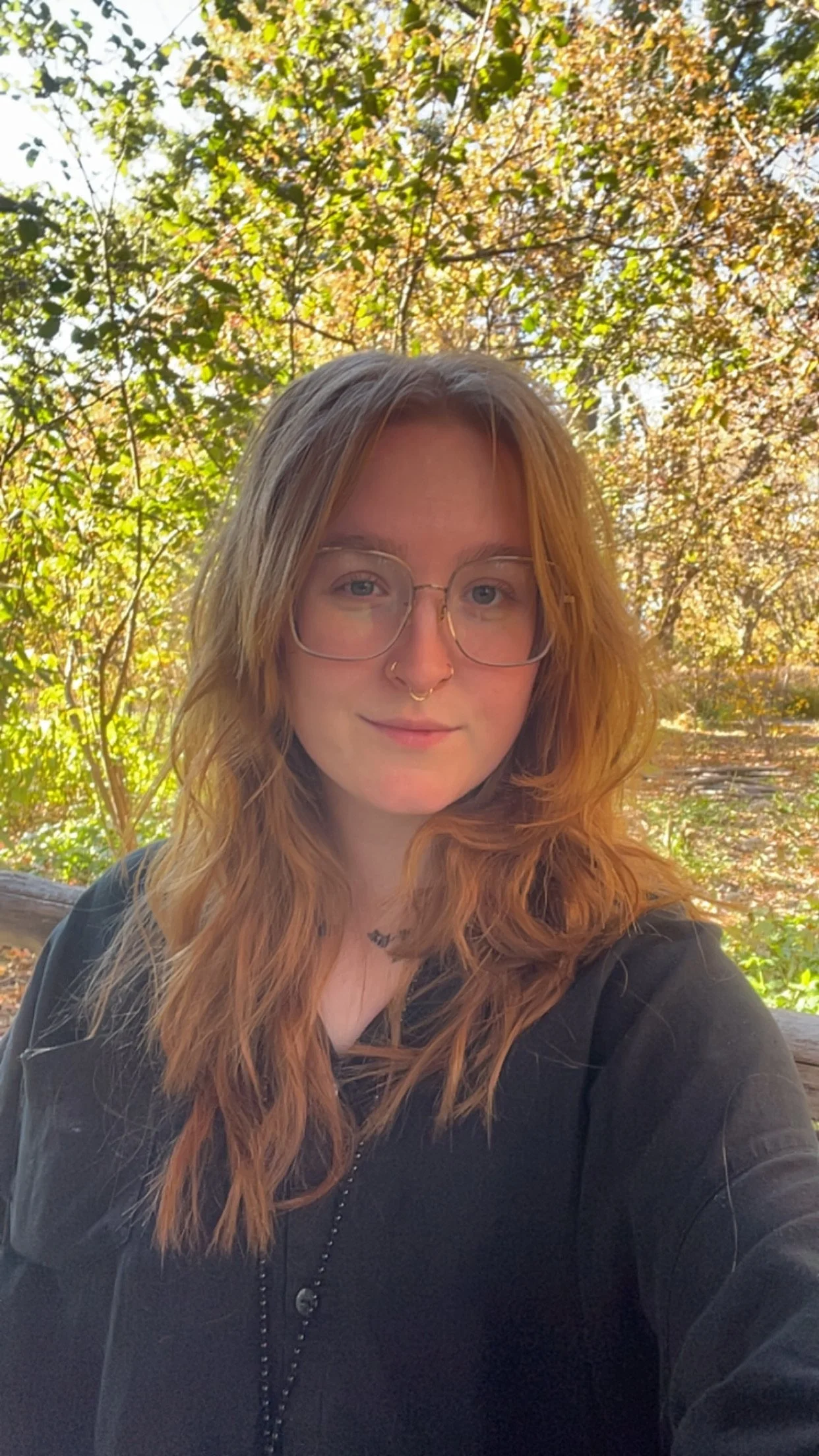 photo of Tabitha, stylist, wearing glasses and in front of foliage