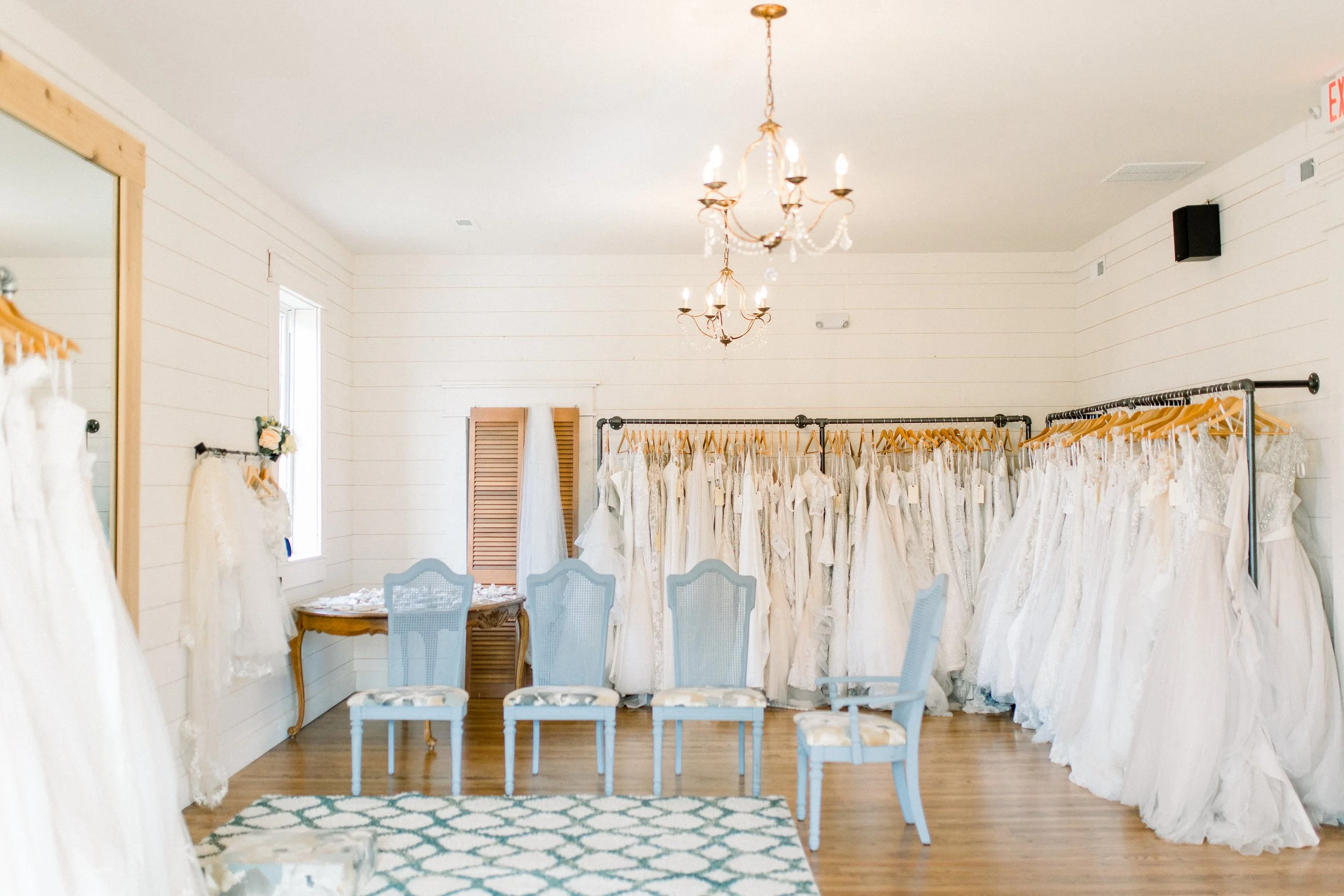 The Attic at Cleo Bridal dress try on room with racks of sample sale wedding gowns and comfortable seating for guests