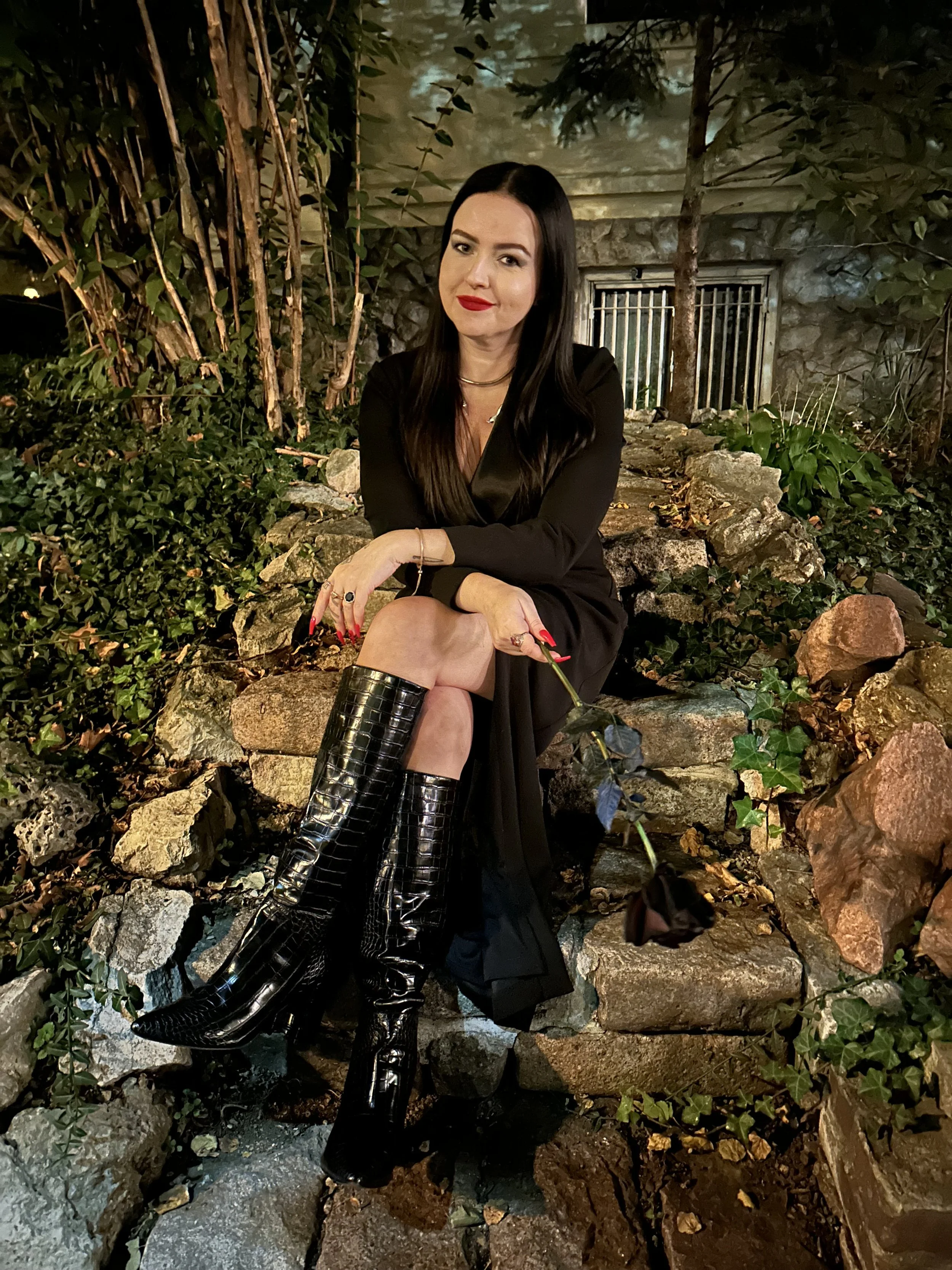 photo of Ermina, stylist, wearing all black, sitting on rocks