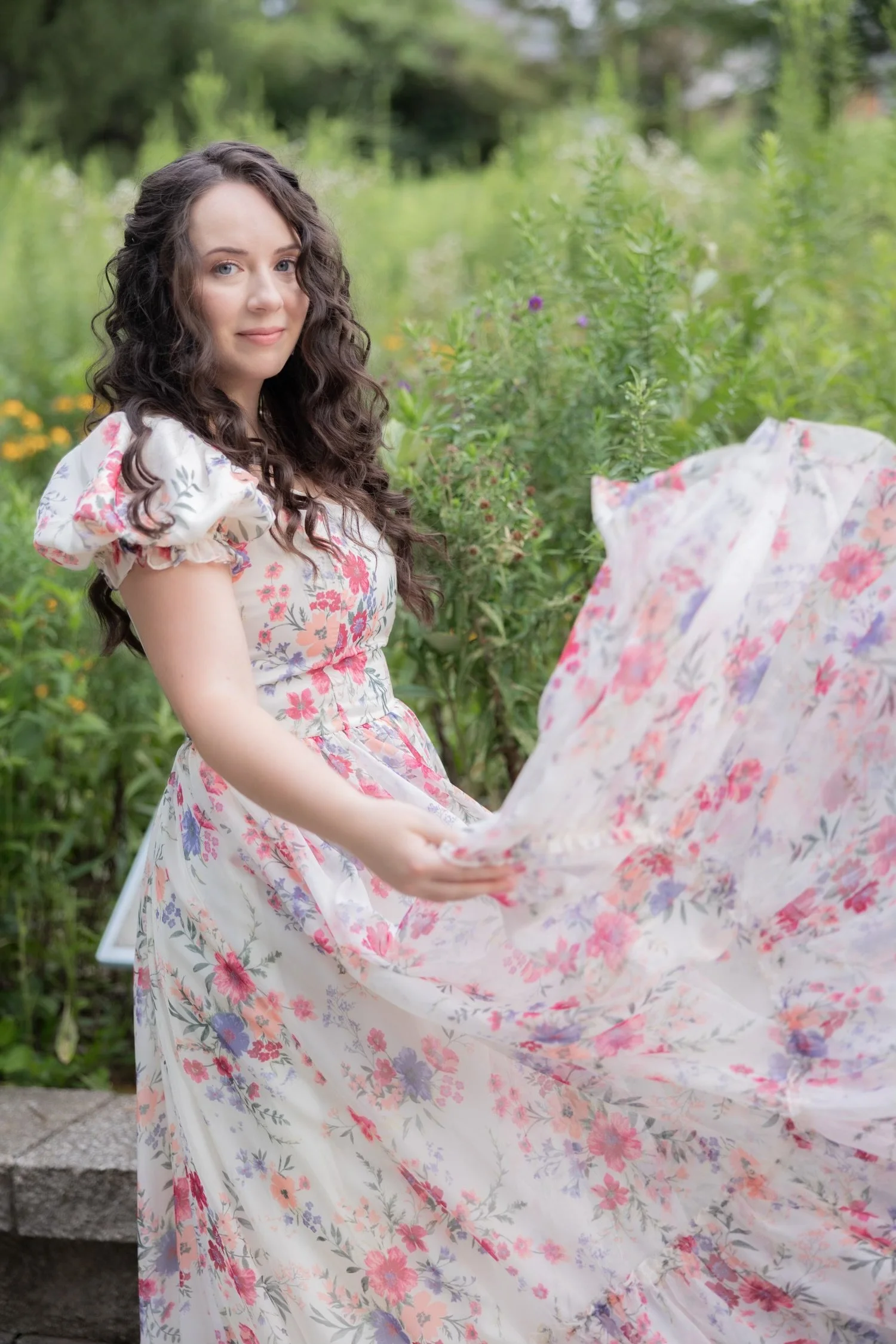 photo of Savanna, stylist, in a white floral dress with tall grass behind her