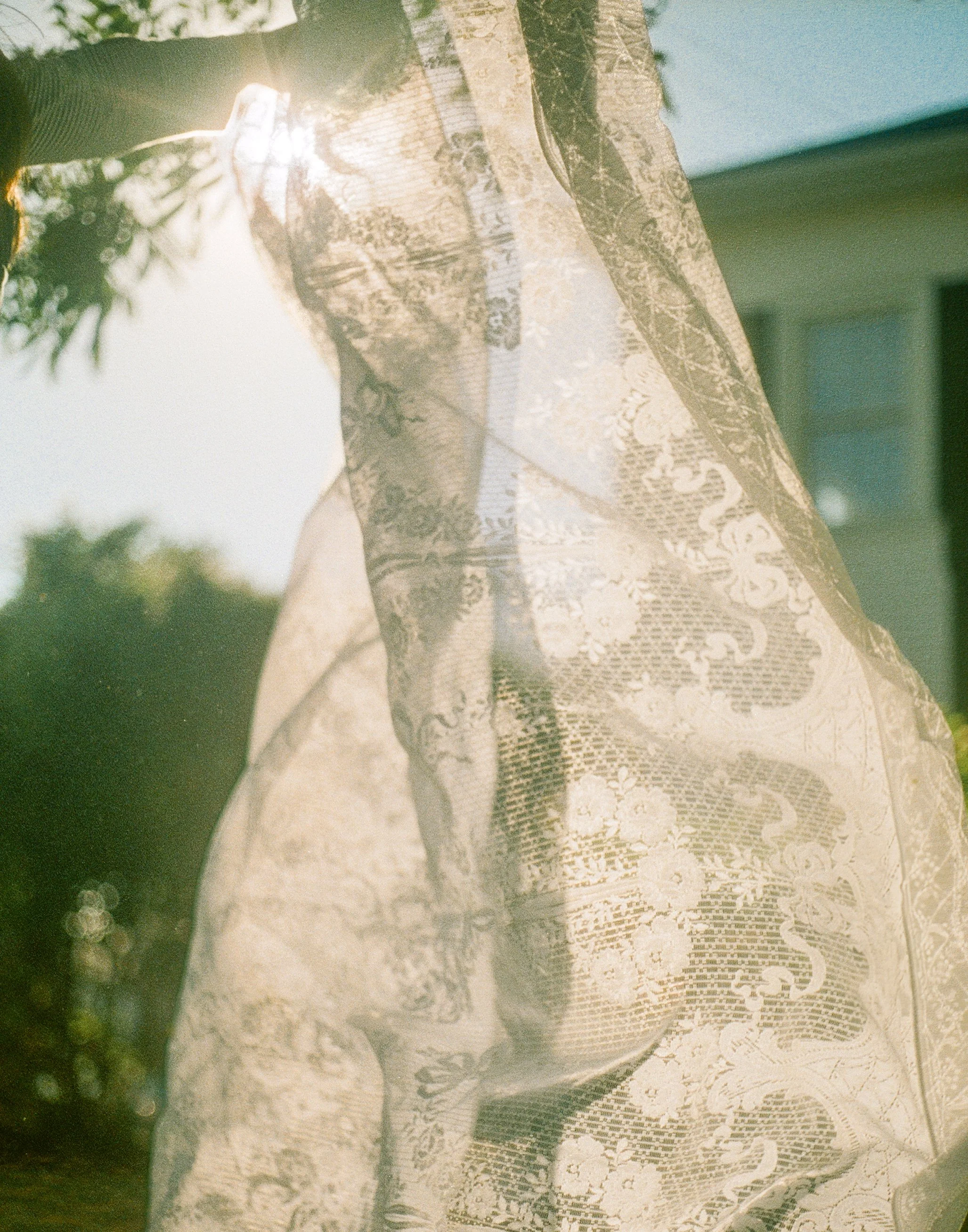 FIlm photo of a sheet of lace blowing in the wind. Link to learn more about cleo bridals history.