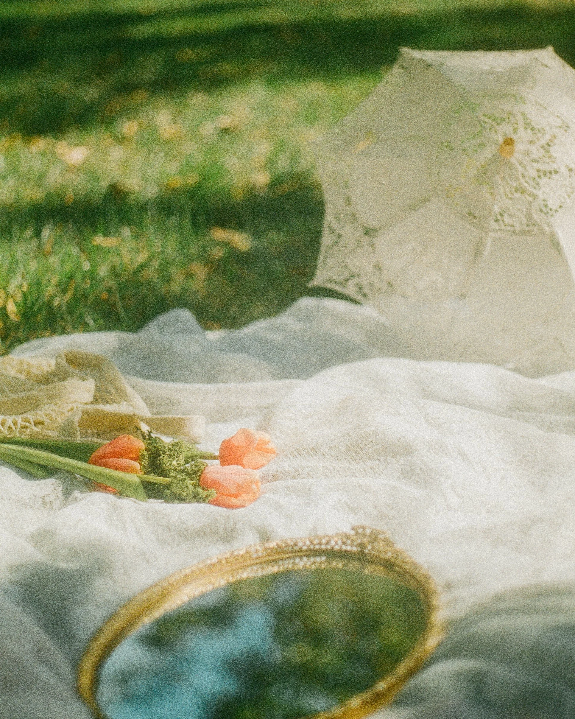 Asethetic lace picnic with orange tulips and a gold filigree mirror. Link to see wedding dress designers.