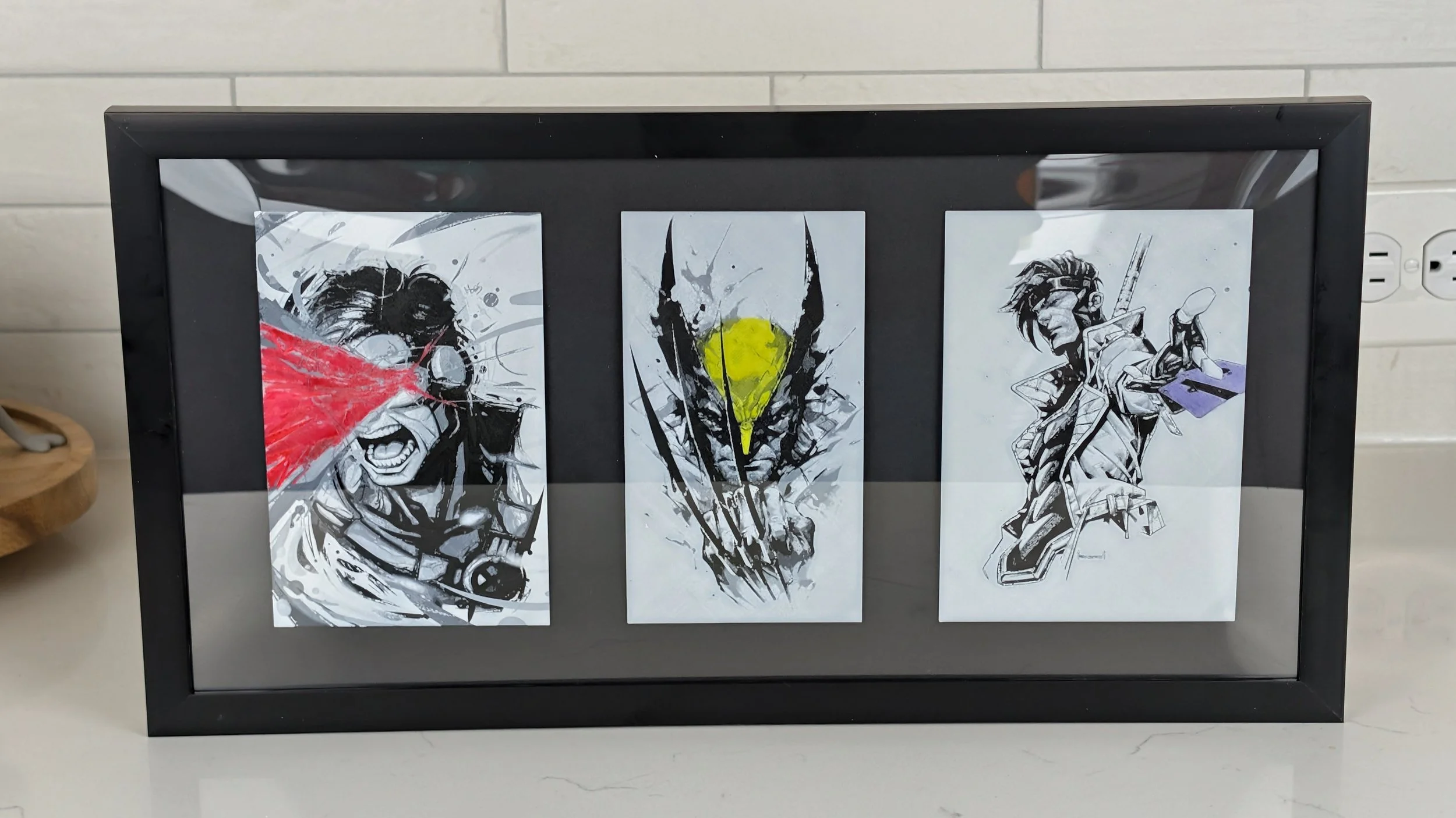 Three black-and-white artistic prints of characters from the game Overwatch, framed and displayed on a black frame.