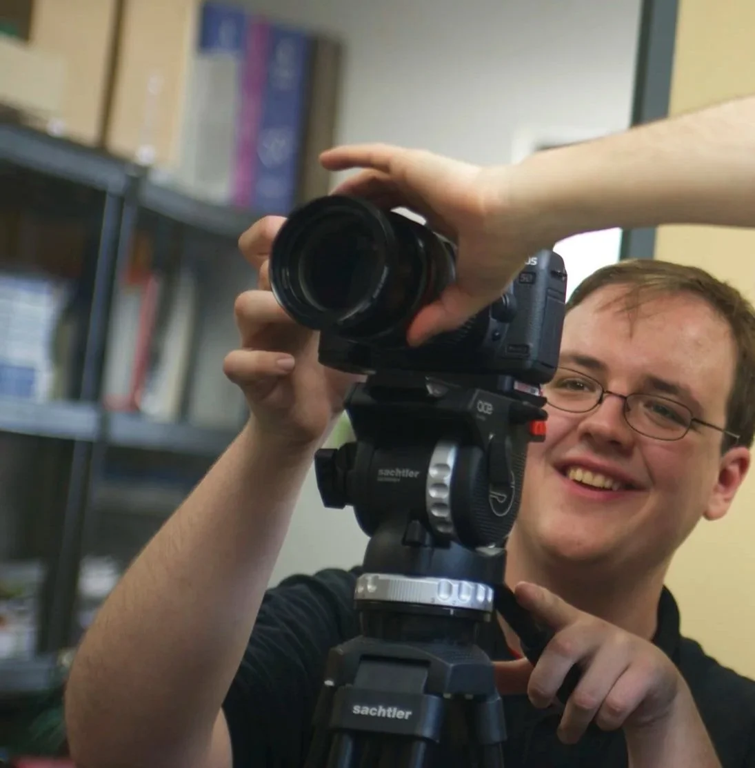Smiling videographer adjusting a professional video camera mounted on a tripod