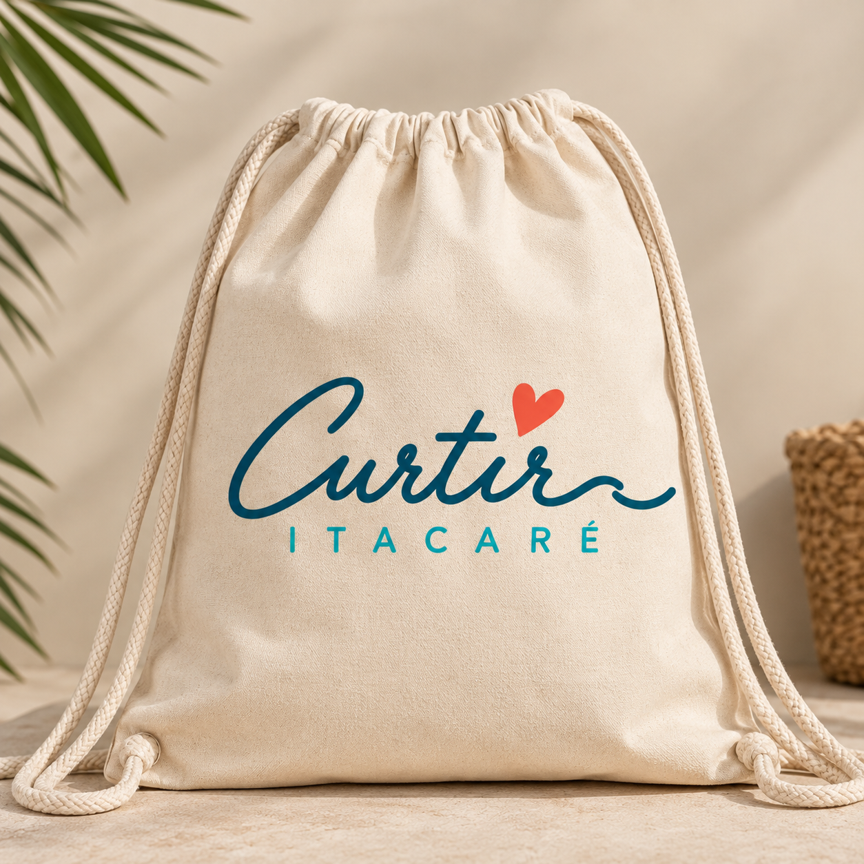 Bolsa de tecido bege com a frase 'Curtir Itacaré' escrita em letras azuis, com um coração vermelho acima do 'i' e fundo branco com detalhes de plantas verdes e uma cesta de palha ao lado.