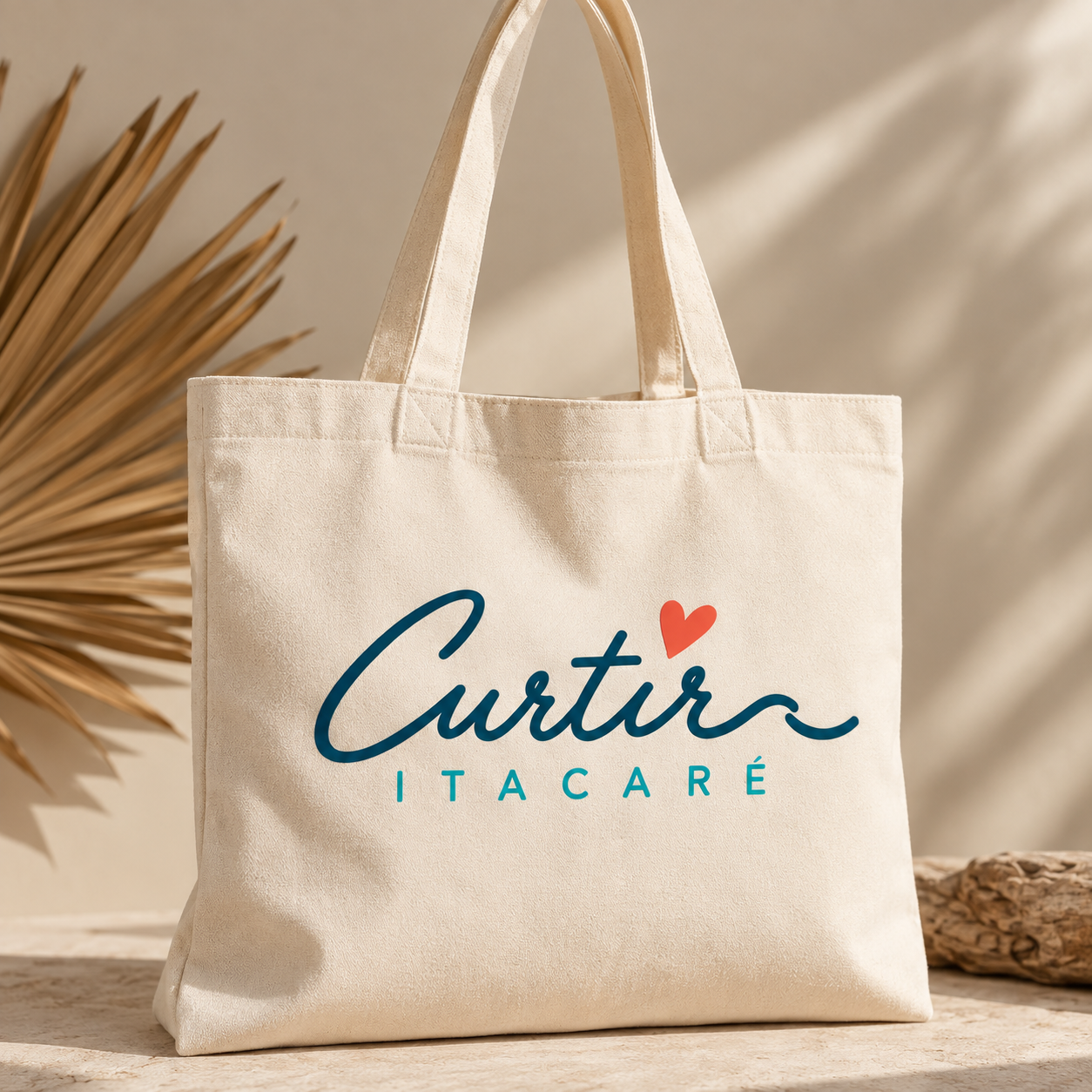 Sacola de tecido bege com texto "Cultura Itacaré" em letras azuis, com coração vermelho no topo da letra "u"; fundo com iluminação suave e elementos decorativos naturais.