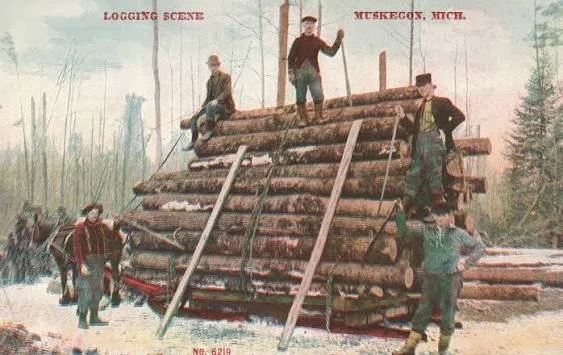Historical photo of men building a log cabin in a snowy forest, with some standing on the structure and others on the ground.