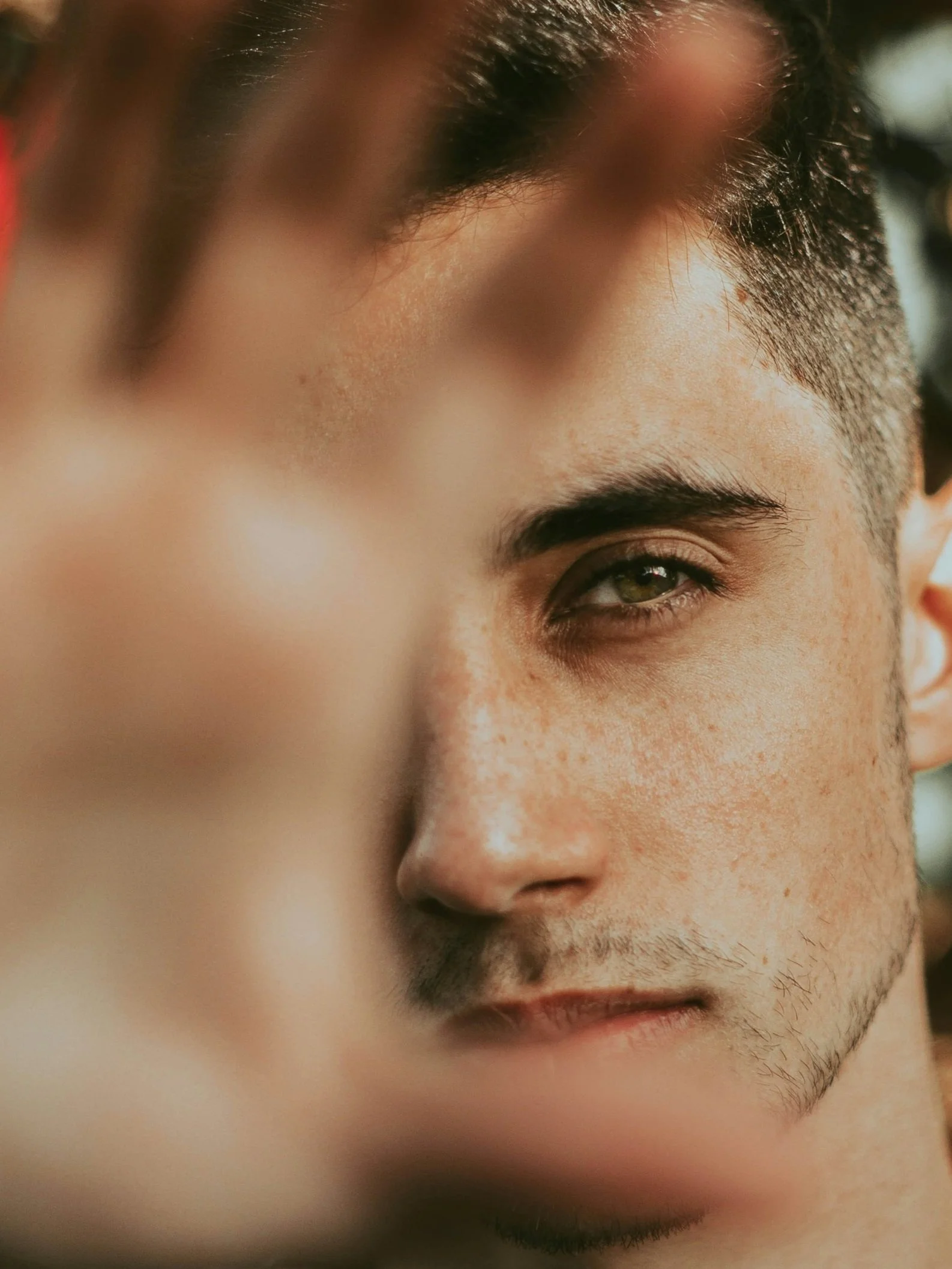 Close-up of a man's face showing one eye, eyebrow, and part of his nose and lips, with a soft focus and warm lighting.