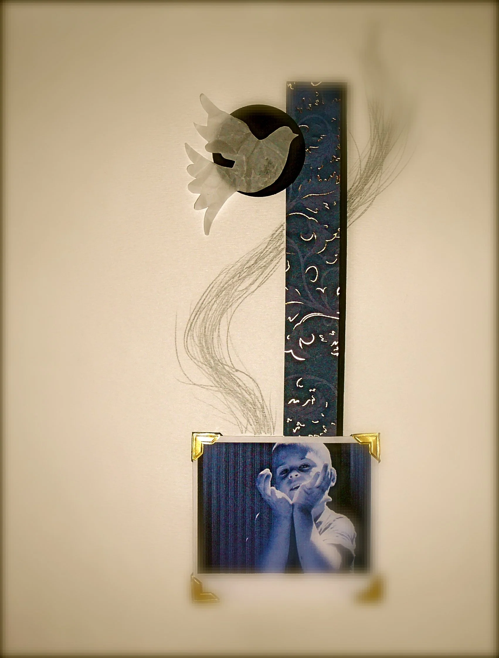 A wall display consisting of a black and white portrait photograph of a young child, a decorative vertical panel with blue and gold patterns, a white paper dove, and abstract line art of a bird in flight.
