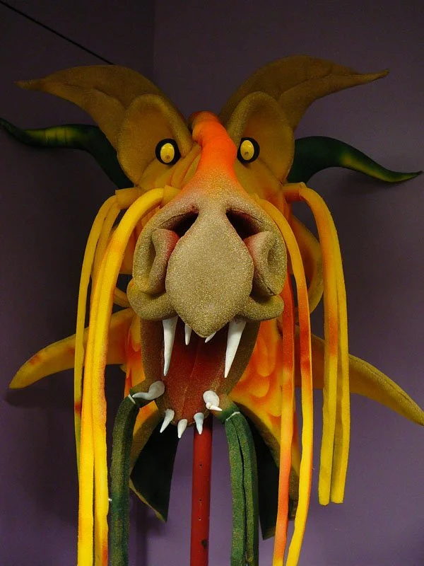 Orange and brown dragon 3D puppet with staring yellow eyes