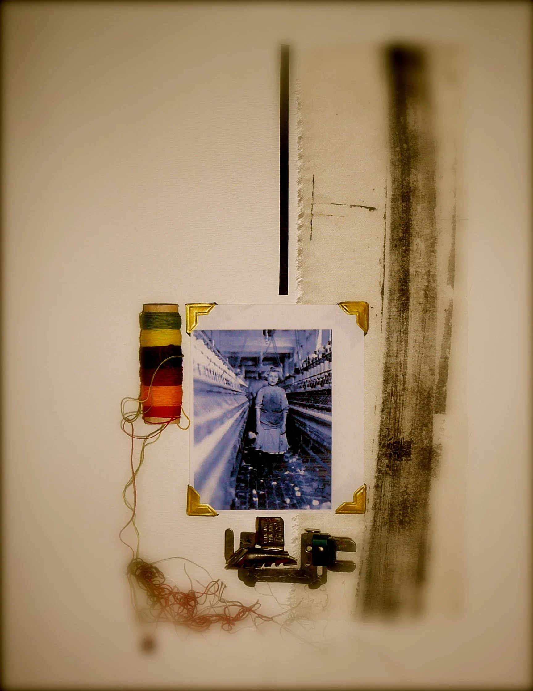 A wall display with a black and white photograph of a person standing on a bridge, surrounded by colorful spools of thread and various sewing tools and supplies.