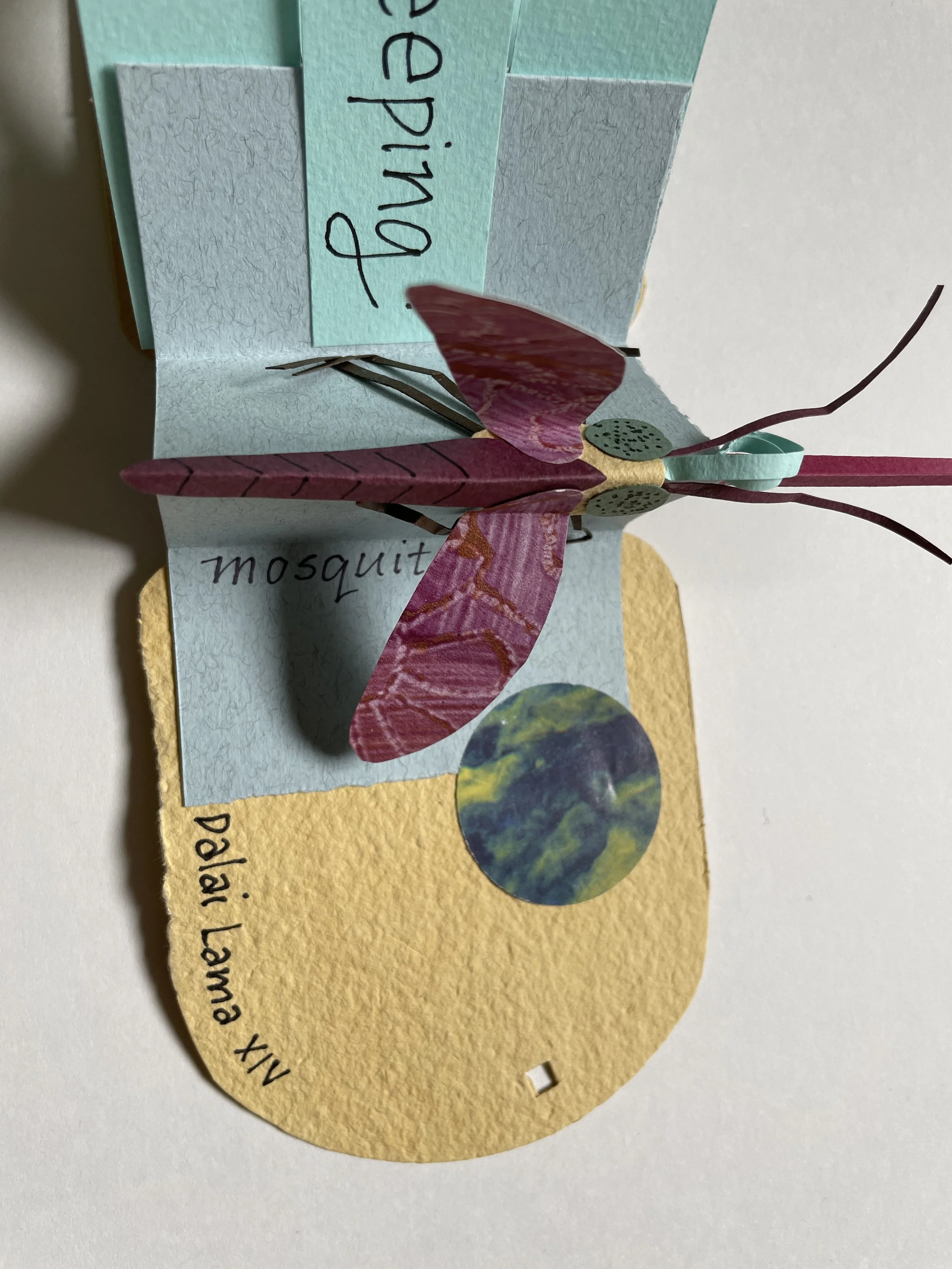 A paper craft of a pink and purple butterfly with green dotted wings, placed on colorful paper notes with handwritten words.
