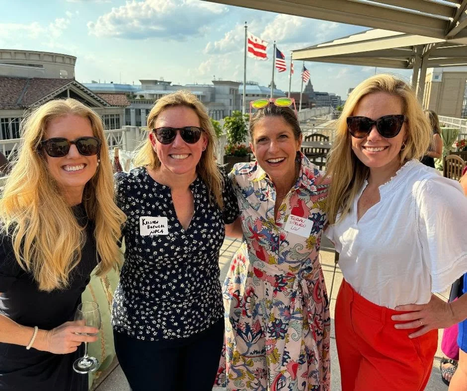 Four women at a summer rooftop reception.