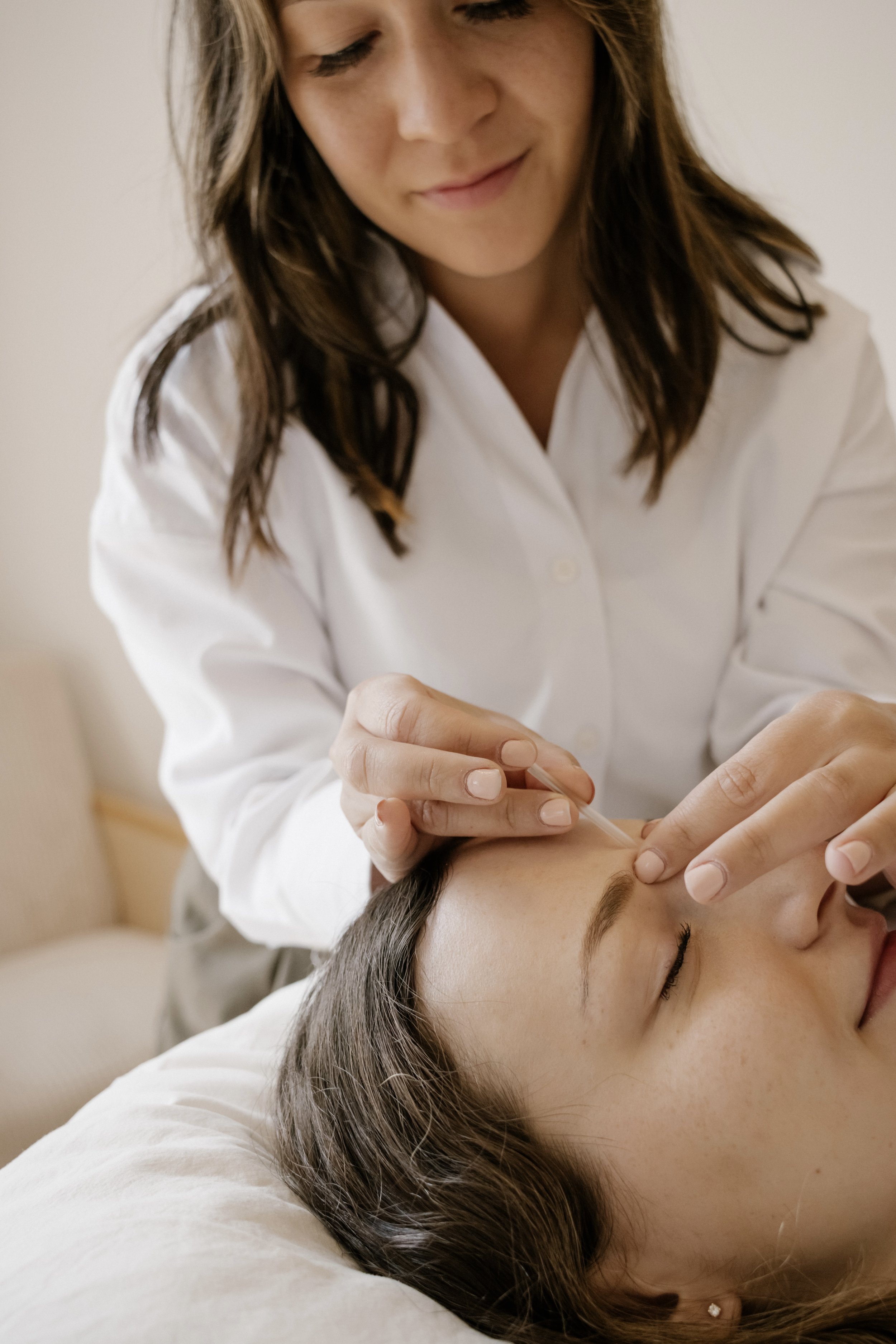 Dr. Sydney Lake ND performs acupuncture on a patient lying with eyes closed, resting on a bed or table, in Victoria BC.