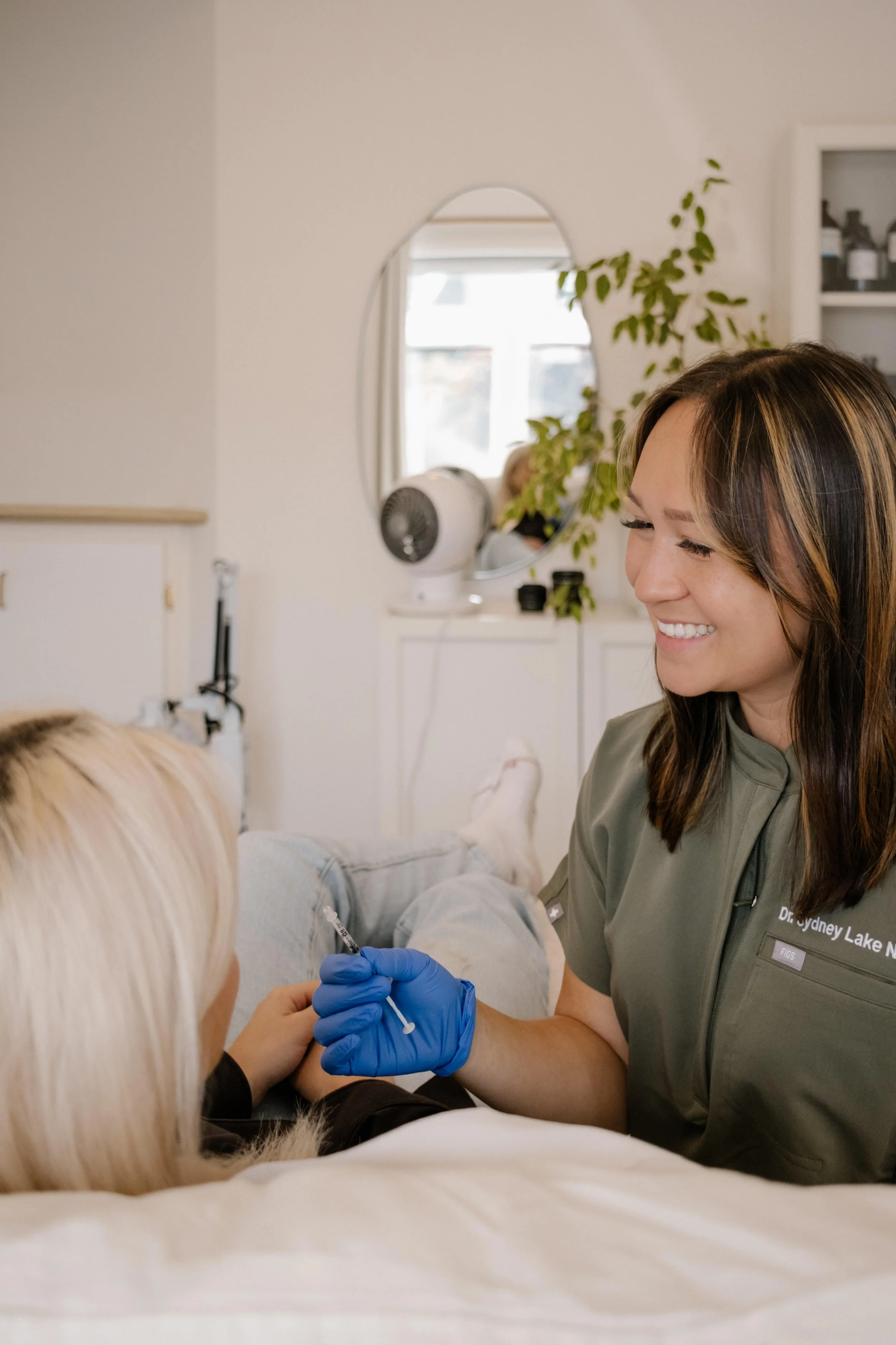 A healthcare professional smiling and administering an injection to a patient.