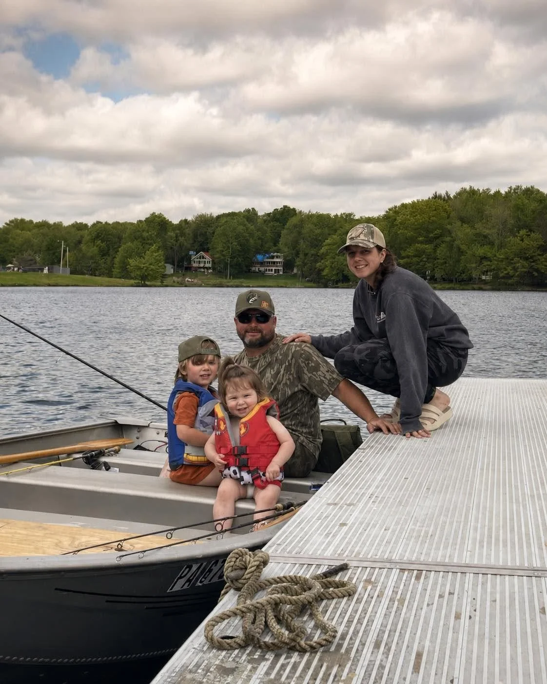 Family gathered beside a jon boat on the lake.