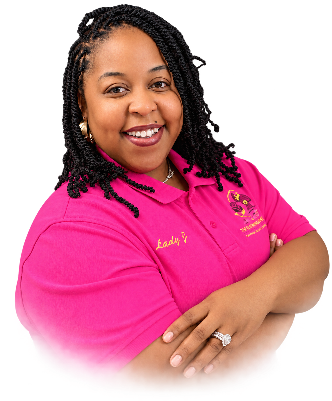 A woman with dark braided hair and a bright smile, wearing a pink polo shirt with embroidered text and logo, standing with her arms crossed.